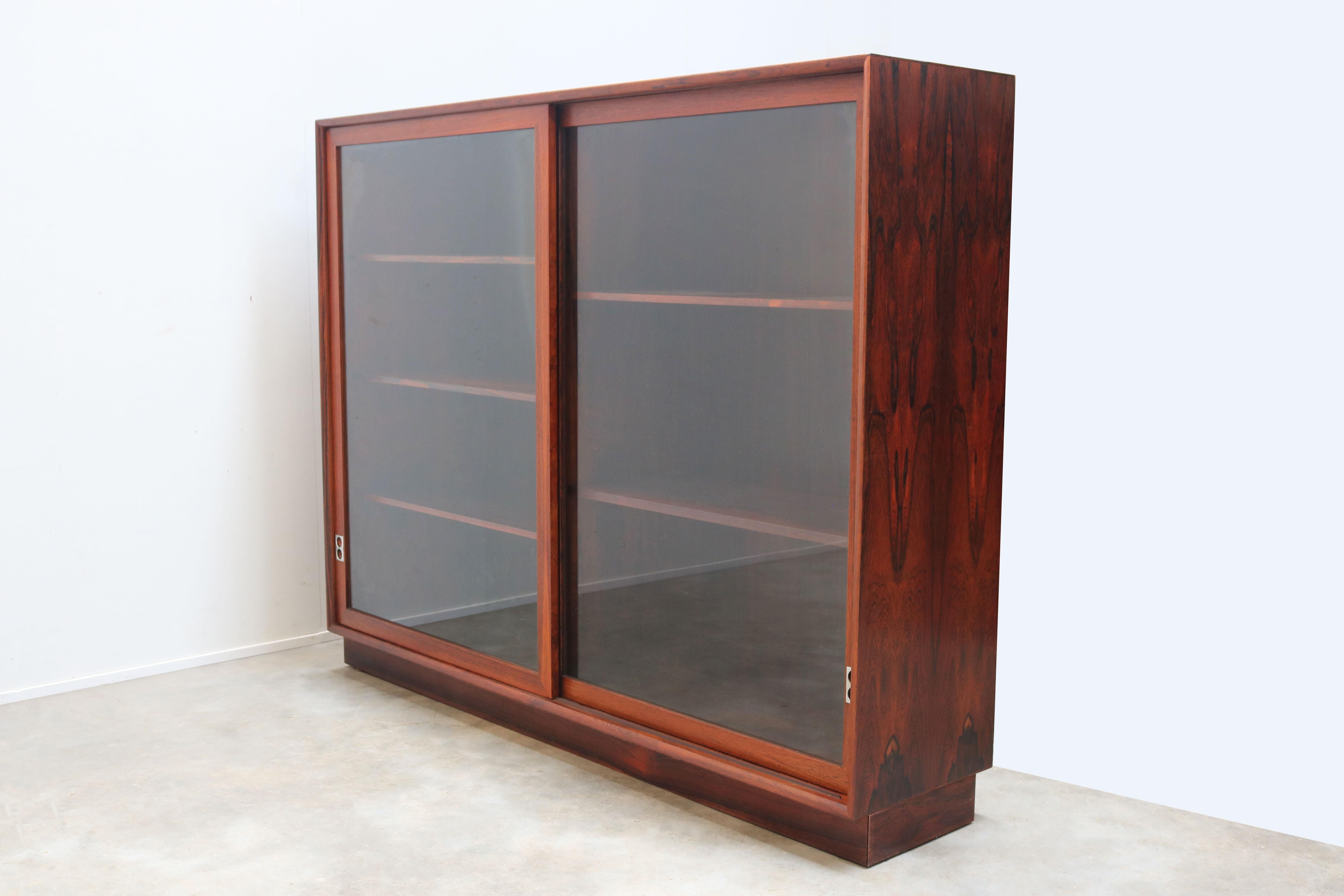 Discover the pinnacle of mid-century modern sophistication with the Arne Vodder rosewood bookcase, featuring two glass sliding doors with aluminum grips, crafted in 1958 for Sibast Furniture. This exquisite piece is not just a bookcase; it is a