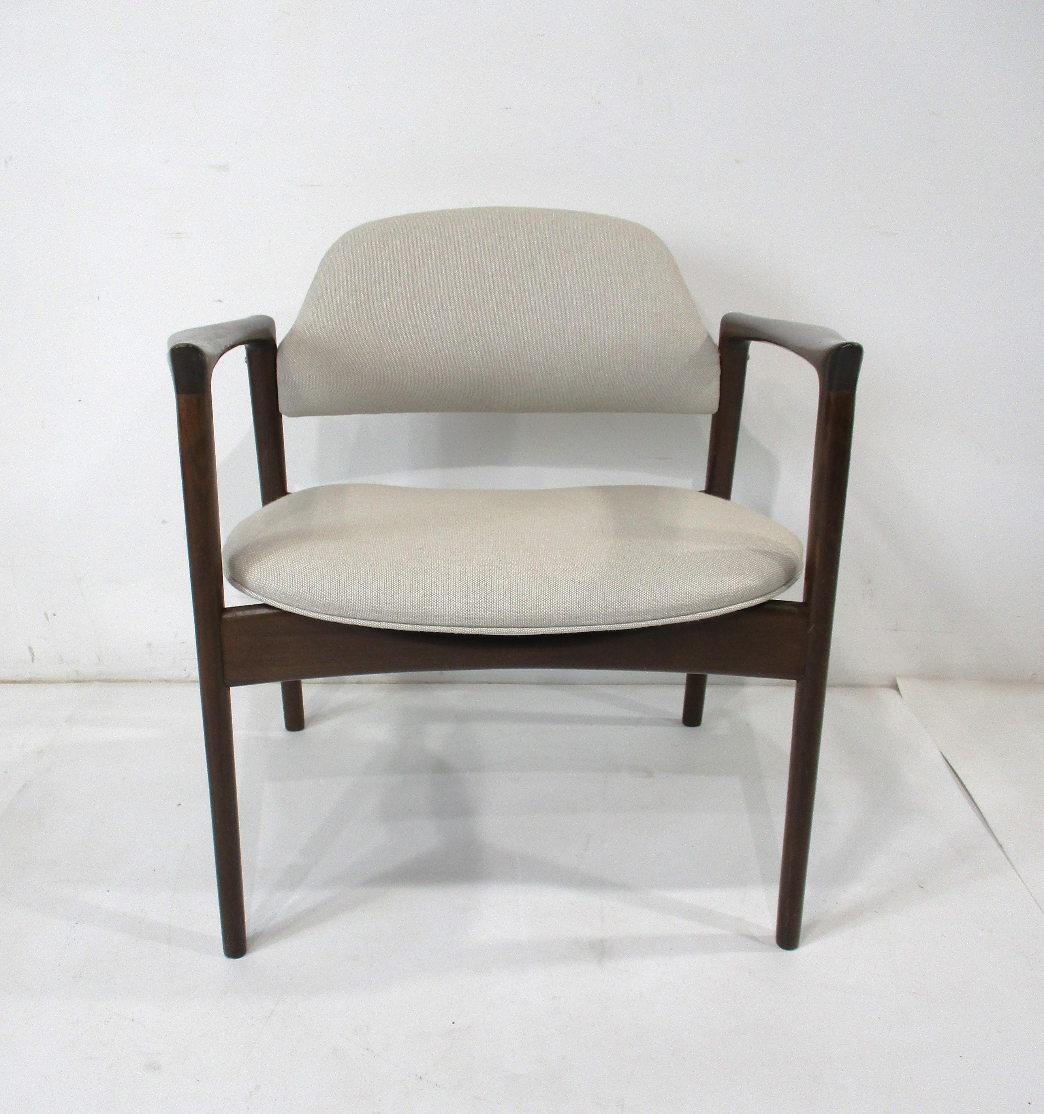 Ce fauteuil de salon aux accoudoirs sculpturaux et à la structure très bien travaillée est fini en noyer foncé avec des ferrures en laiton et recouvert d'un tissu de couleur avoine avec un peu de couleur taupe plus claire. Les nouveaux tissus