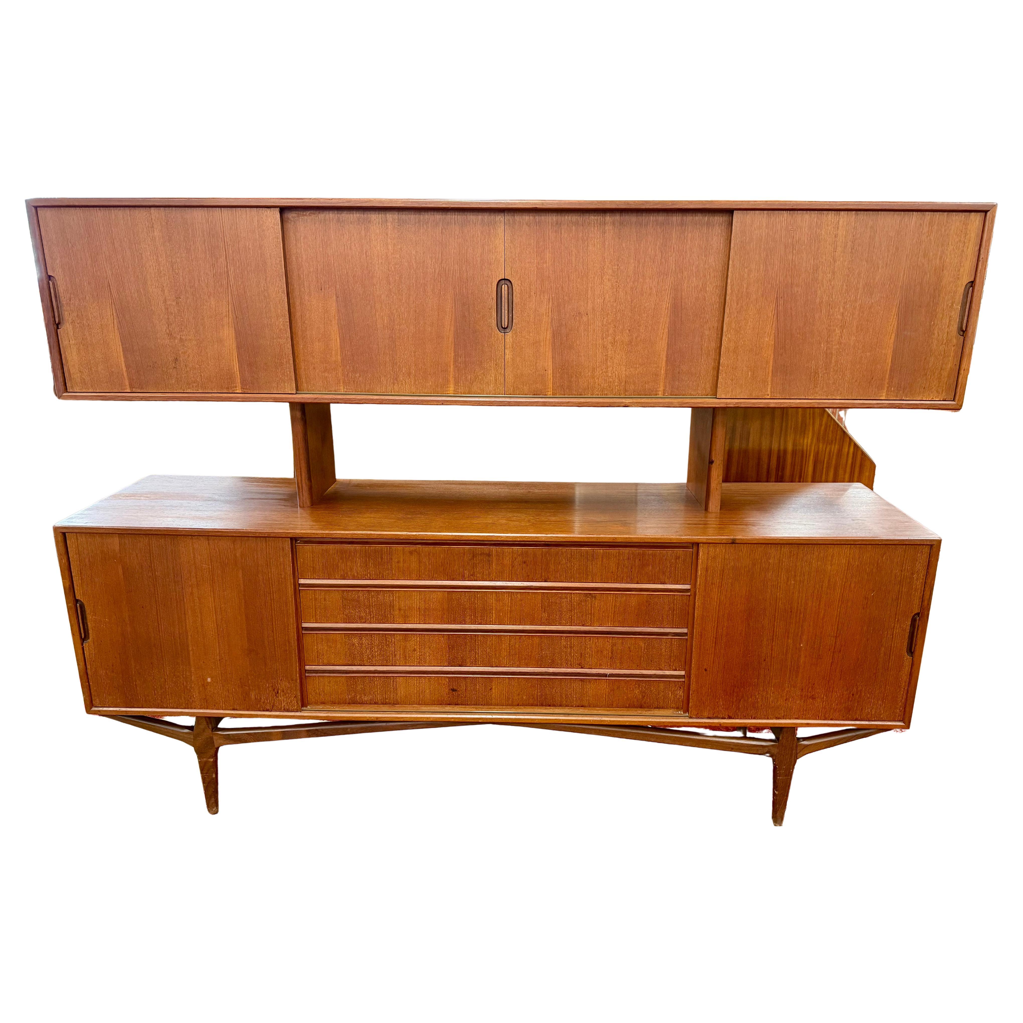 The Danish Mid Century Modern Knud Nielsen 2 Tier Floating Sideboard Cabinet Buffet is a stylish and functional piece of furniture from the 1960s. Made of teak with a brown color, this cabinet features a sliding wood door and multiple shelves for