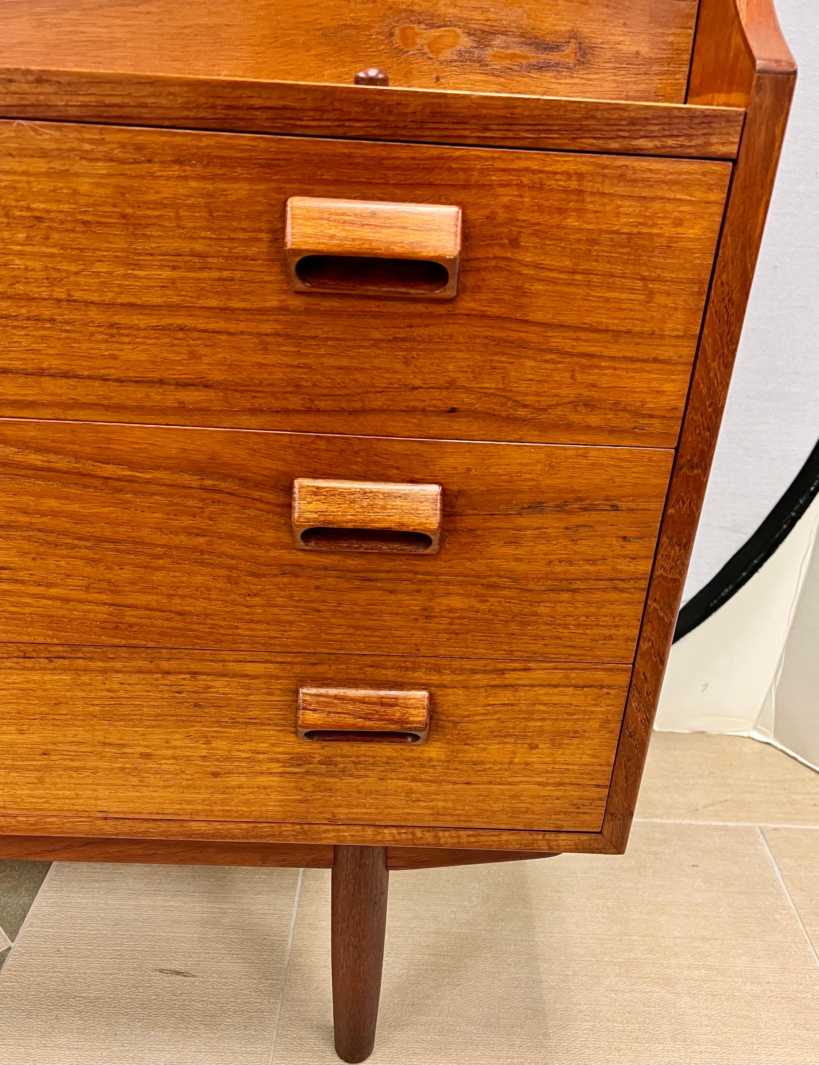 Mid century Borge Morgensen teak secretary desk is part desk, part storage. Bottom part has three drawers. Top leaf drops down into a writing surface. Multifunctional and elegant, this desk can serve as both a desk and an entryway piece. Great