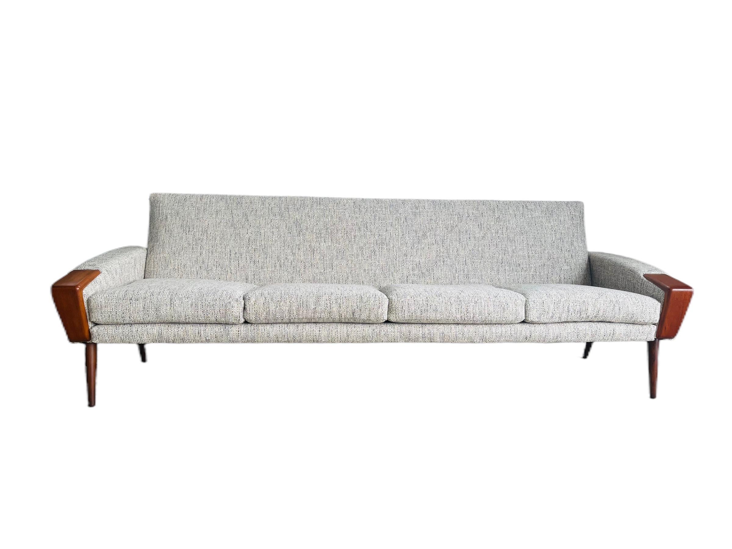 Stunning rare mid-century Danish modern teak sofa designed by N.A. Jørgensens for Bramin Mobler of Denmark. This gorgeous sofa is newly restored and reupholstered. This sofa features beautiful teak accent on each arm and teak tapered legs.