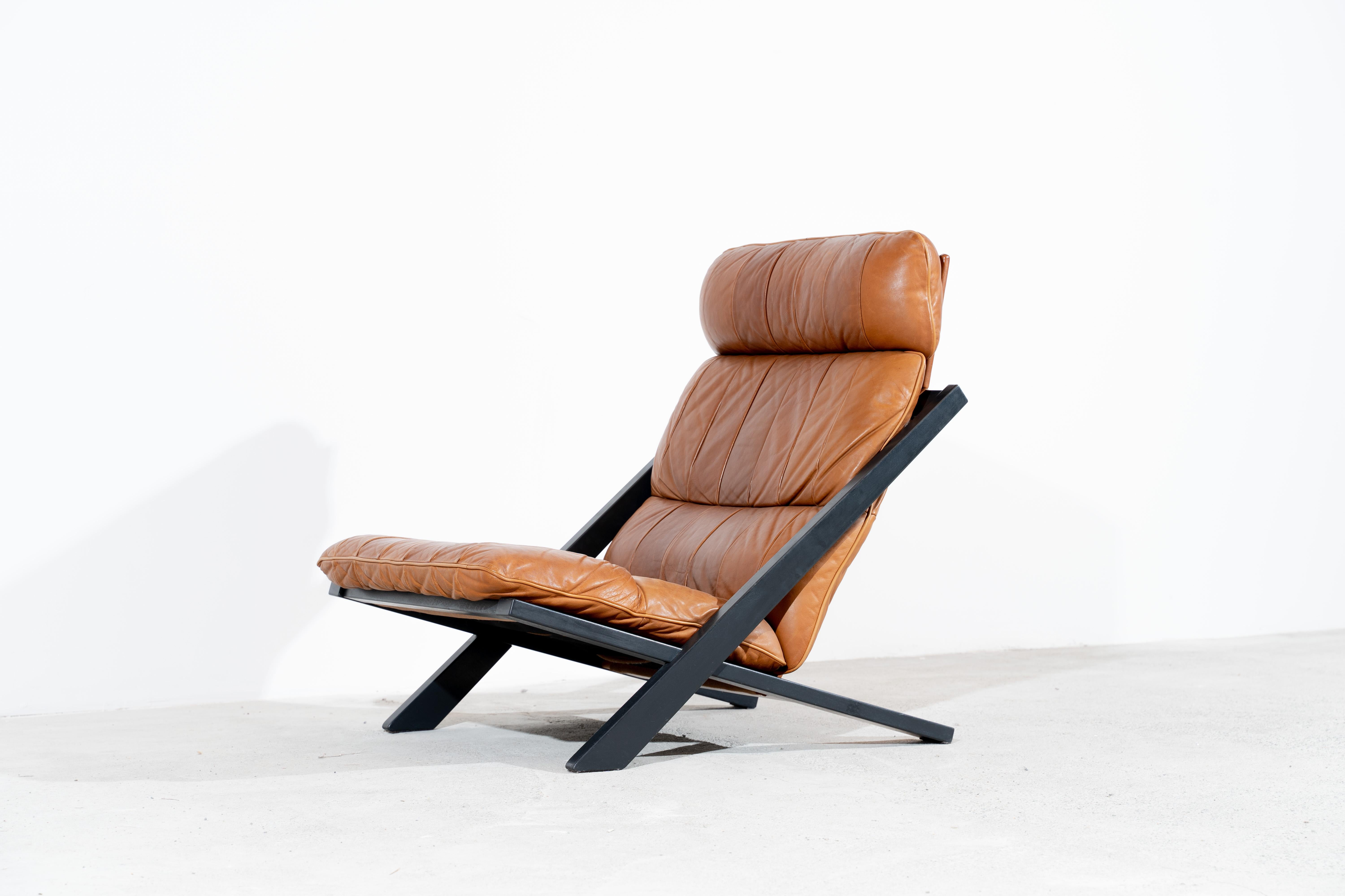 Rare and wonderful high back lounge chair designed by Ueli Berger and produced by De Sede, Switzerland in the 1970s. Beautiful patinated cognac leather and original matt lacquered dark grey base/frame.
 