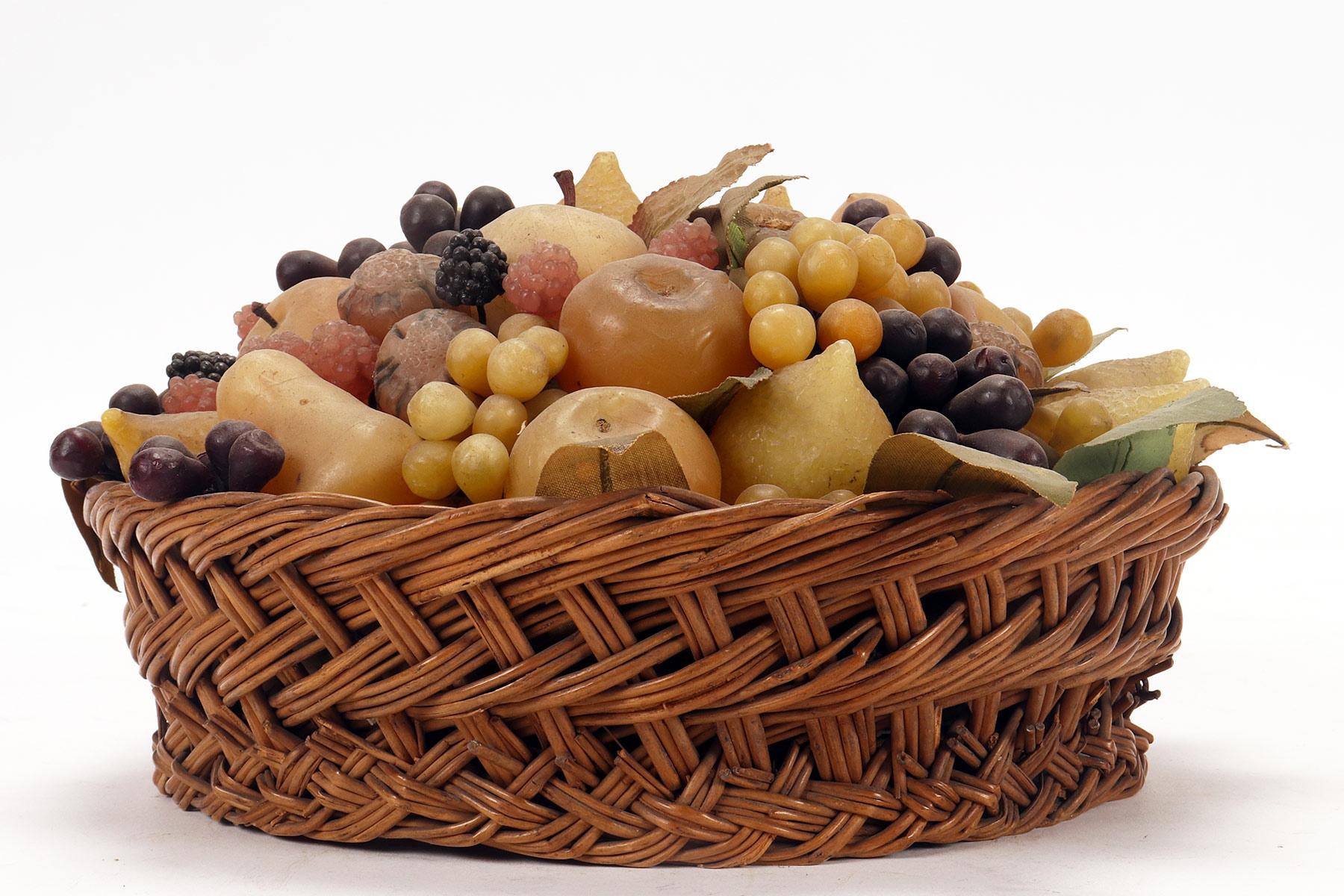 A rare decorative fruit basket made of wax. The elegant wicker basket contains an arrangement of colored wax fruit. The branches and leaves are made of wire, paper and colored fabric. Among the fruit, we recognize blackberries, pears, gooseberries,