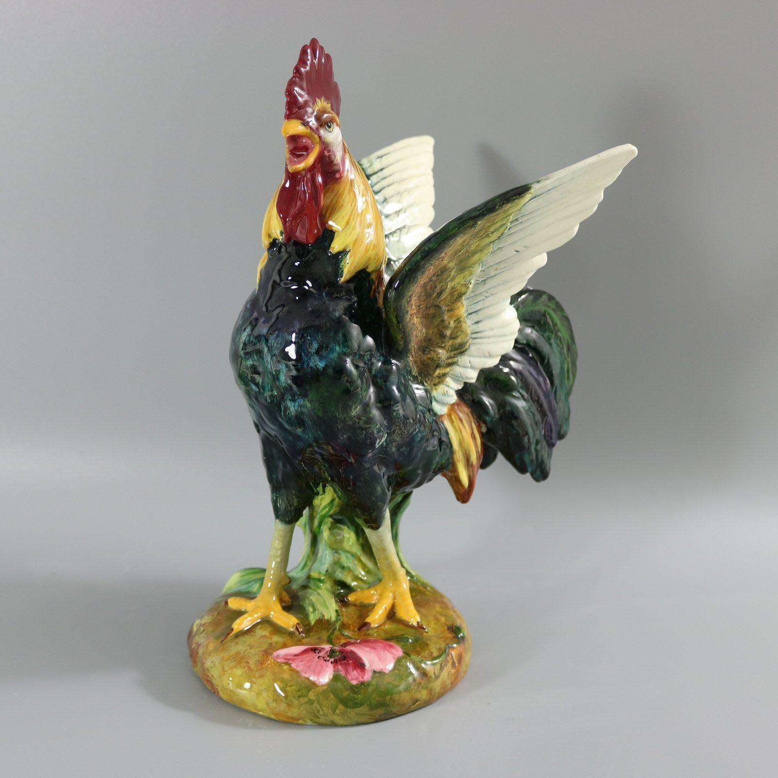 Delphin Massier French Majolica figural vase which features a crowing rooster with it's wings outstretched. A hand painted flower on the base. Colouration: teal blue white, yellow, are predominant. The piece bears maker's marks for the Delphin