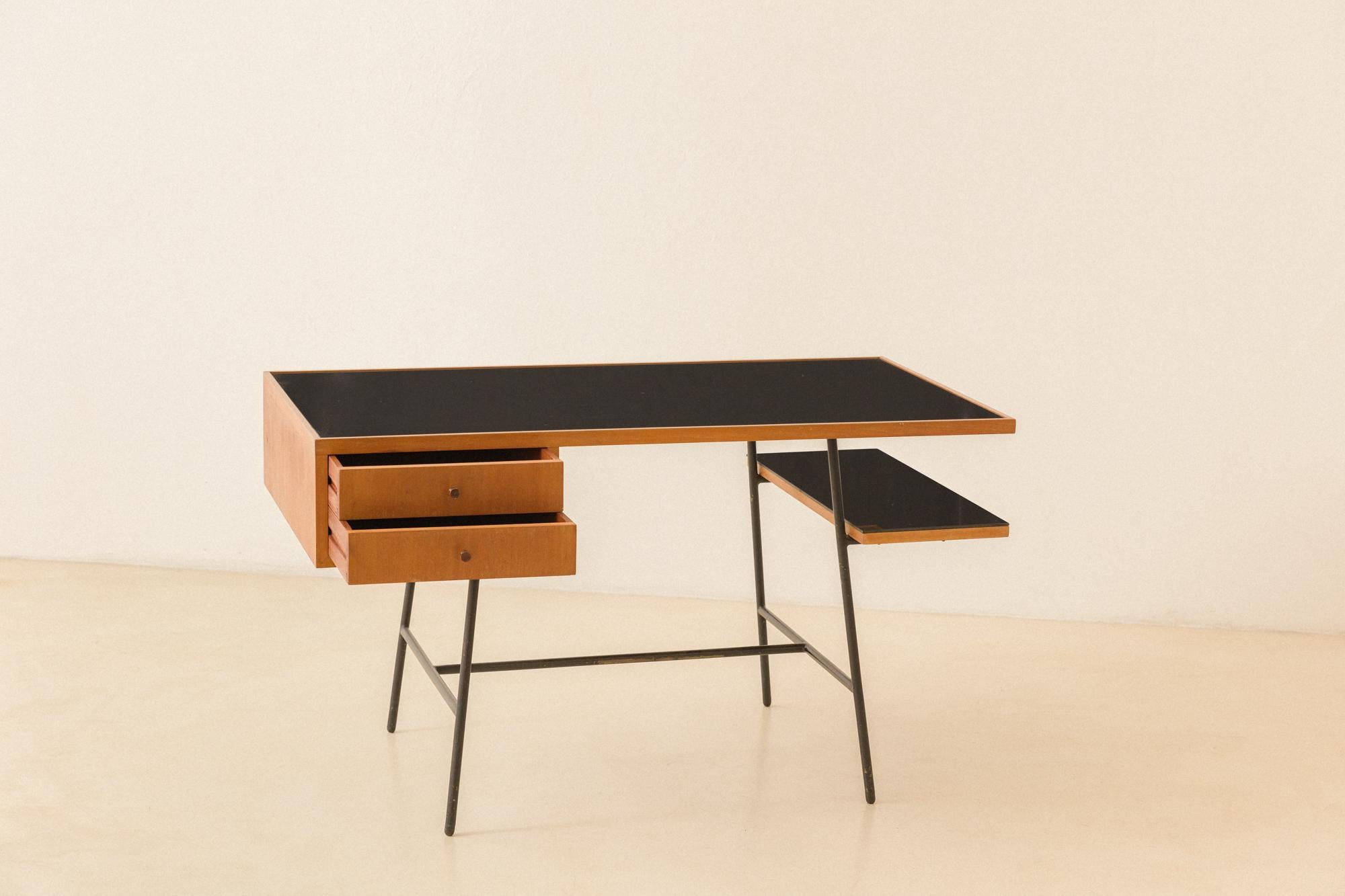 This desk was designed between 1950 and 1953 and stood out within the production of Hauner and Eisler's Móveis Artesanal. The desk has an iron structure with a top in Pau-marfim wood and painted-black glass tops, with two drawers and a shelf.
