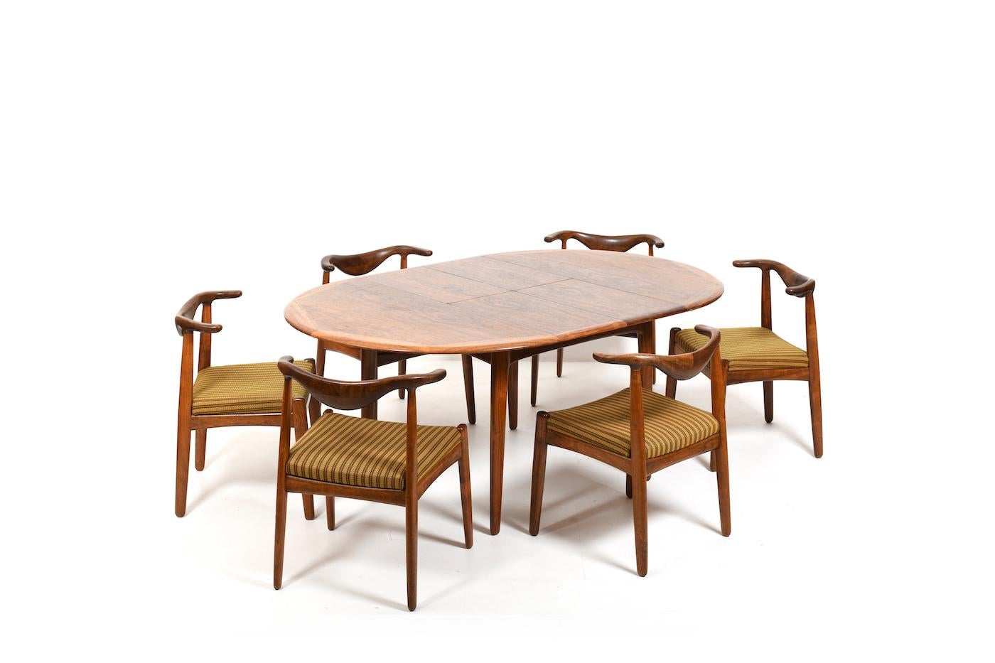 Very rare danish dining room set incl. 6 cowhorn chairs, round / oval table and the matching cabinet by Svend Aage Madsen. The whole ensemble made in finest walnut. Table with retractable leaves to enlarge the table top. Cabinet inside with drawers.