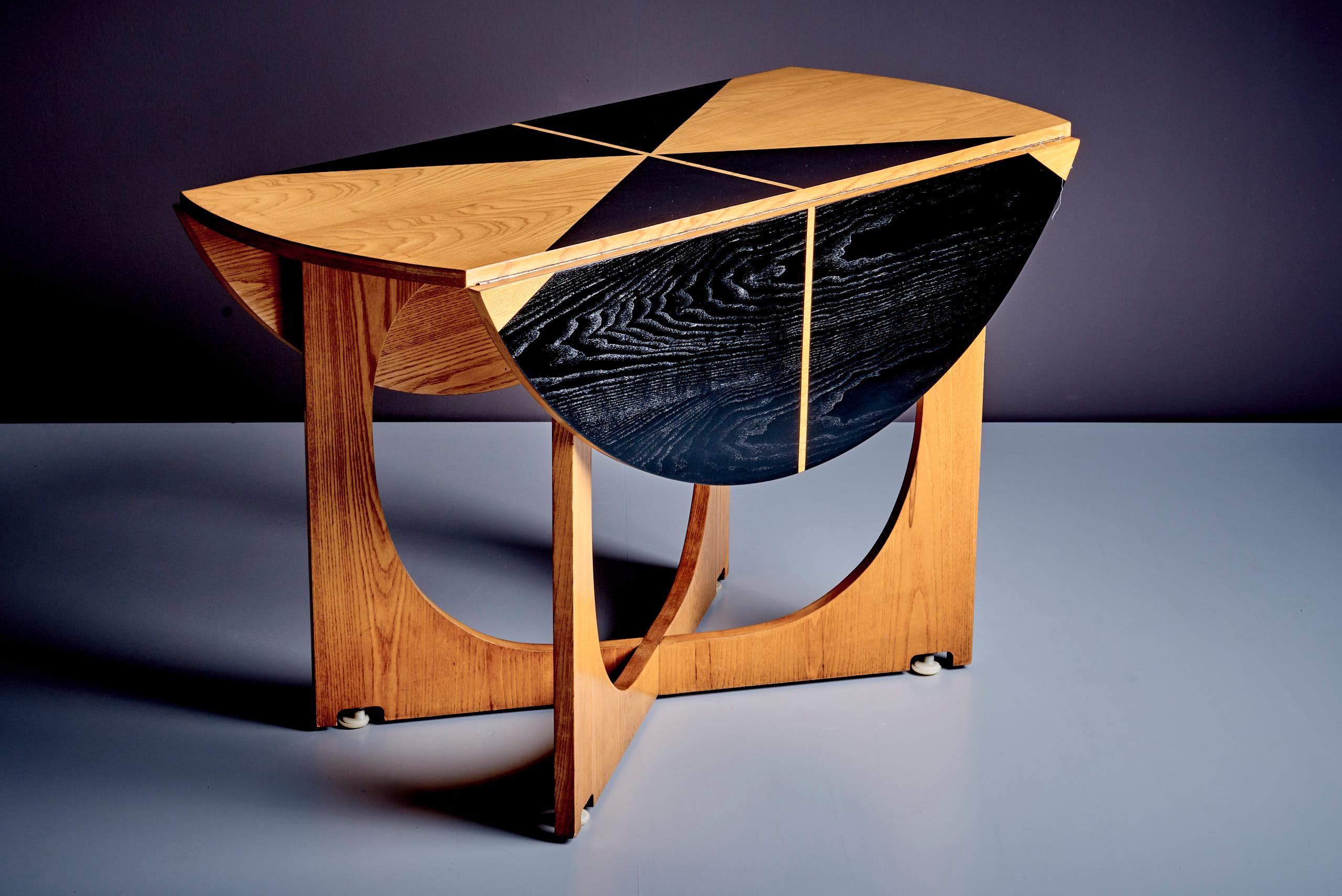 This exceptional drop-leaf table is part of the Apta series, designed by Gio Ponti and produced by Walter Ponti in Italy in 1970. The table features a plywood structure and a striking geometric tabletop pattern in black and natural wood, showcasing