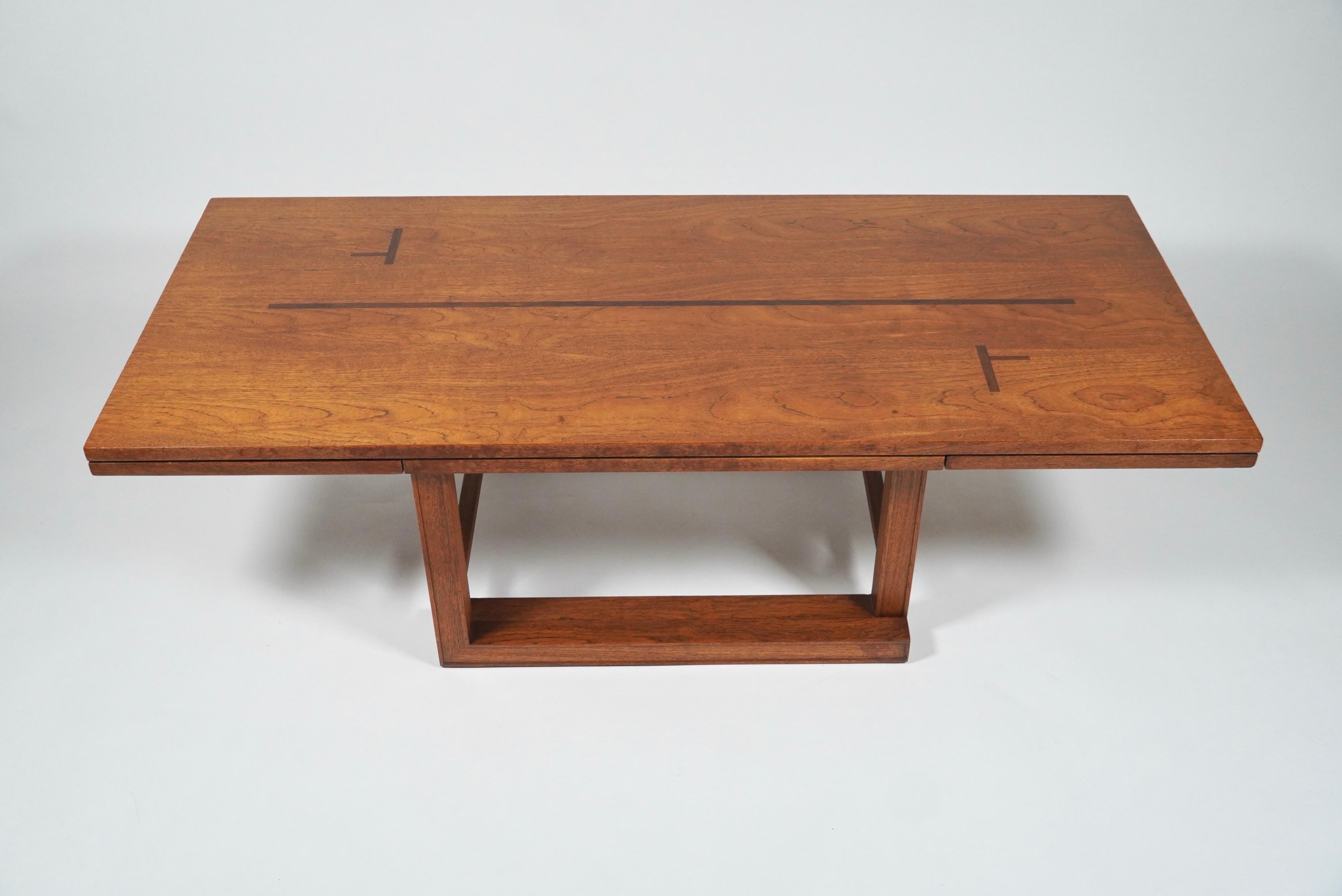 A rare and unusual design by Edward Wormley for Dunbar is this camel leg coffee table that converts into a low console table with drop leaf sides. The top and leafs have an abstract design of inlaid mahogany reminiscent of the Taliesin West School