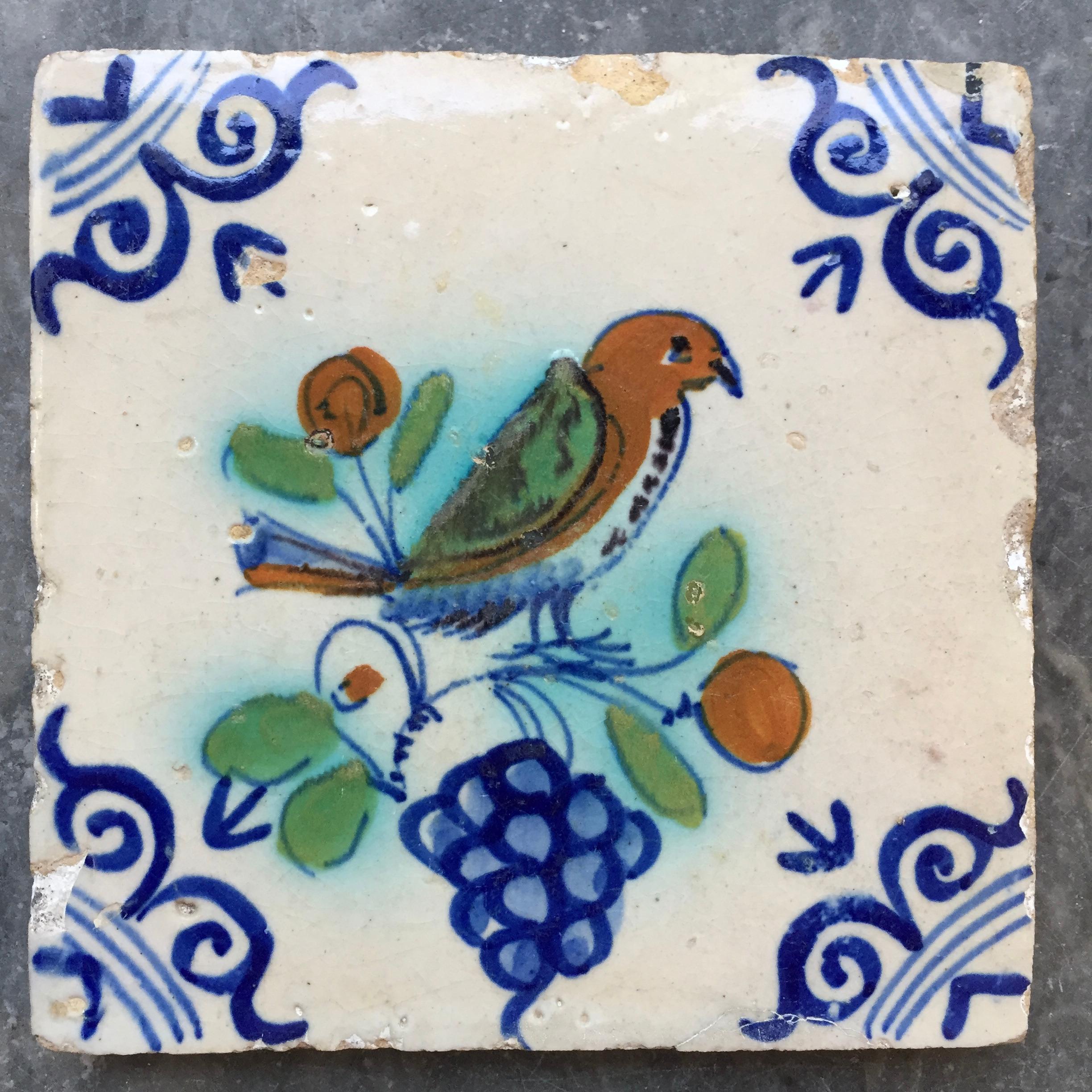 The Netherlands
Circa 1620 - 1640

A Dutch Delft tile painted with a fine and large bird sitting on a grapevine. A nice large image, fine painted, and bright colors. 
With so-called oxheads as corner decoration.

A genuine collectible of 400