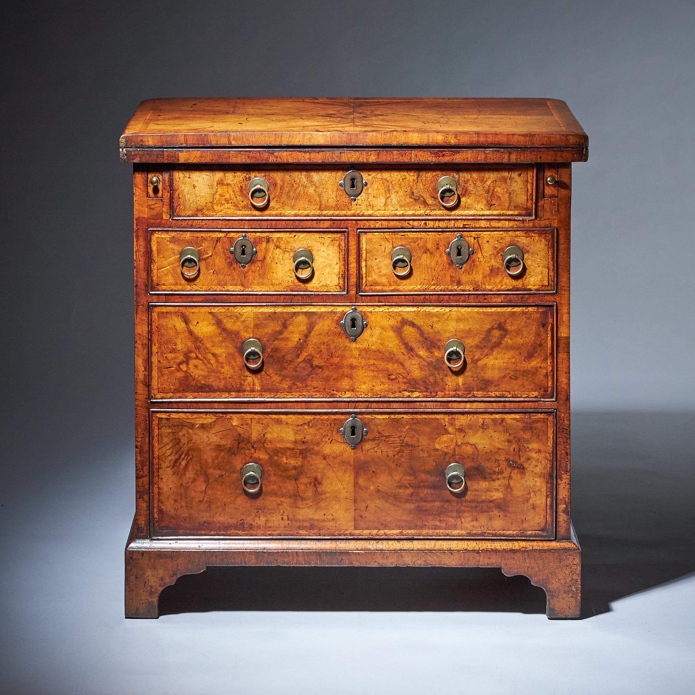 A fine and rare early 18th-century compact George I figured walnut bachelors chest

The quarter veneered feather and crossbanded top opens on original hinges to reveal a veneered interior of six book-matched sections similarly feather and