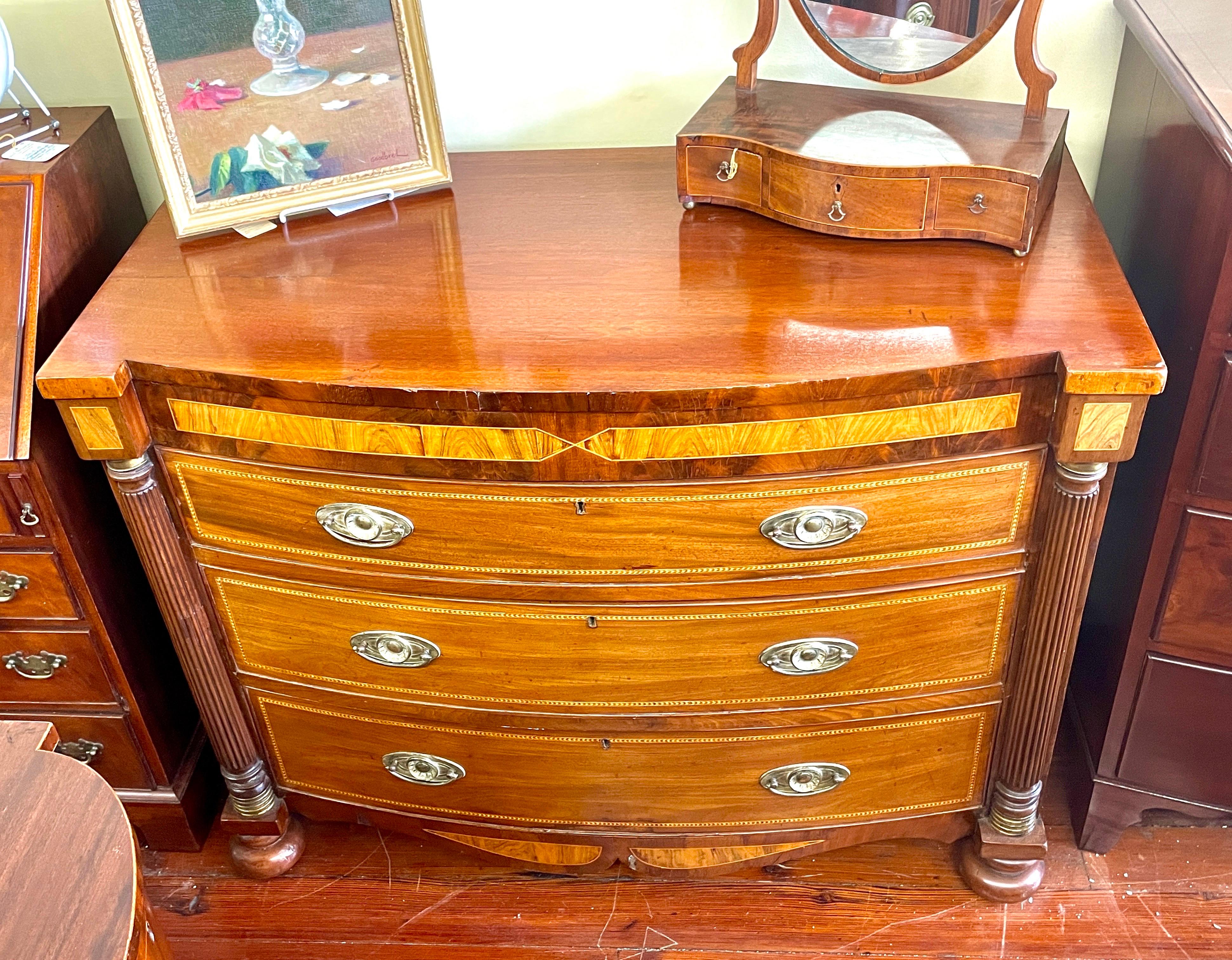 A rare and important Antique American mid-Atlantic region Late Empire Inlaid mahogany large Bowfront Chest of Drawers with checkered inlays, rosewood crossbanding (inlay), half-turned and reeded columns with brass capitals top and bottom; all upon