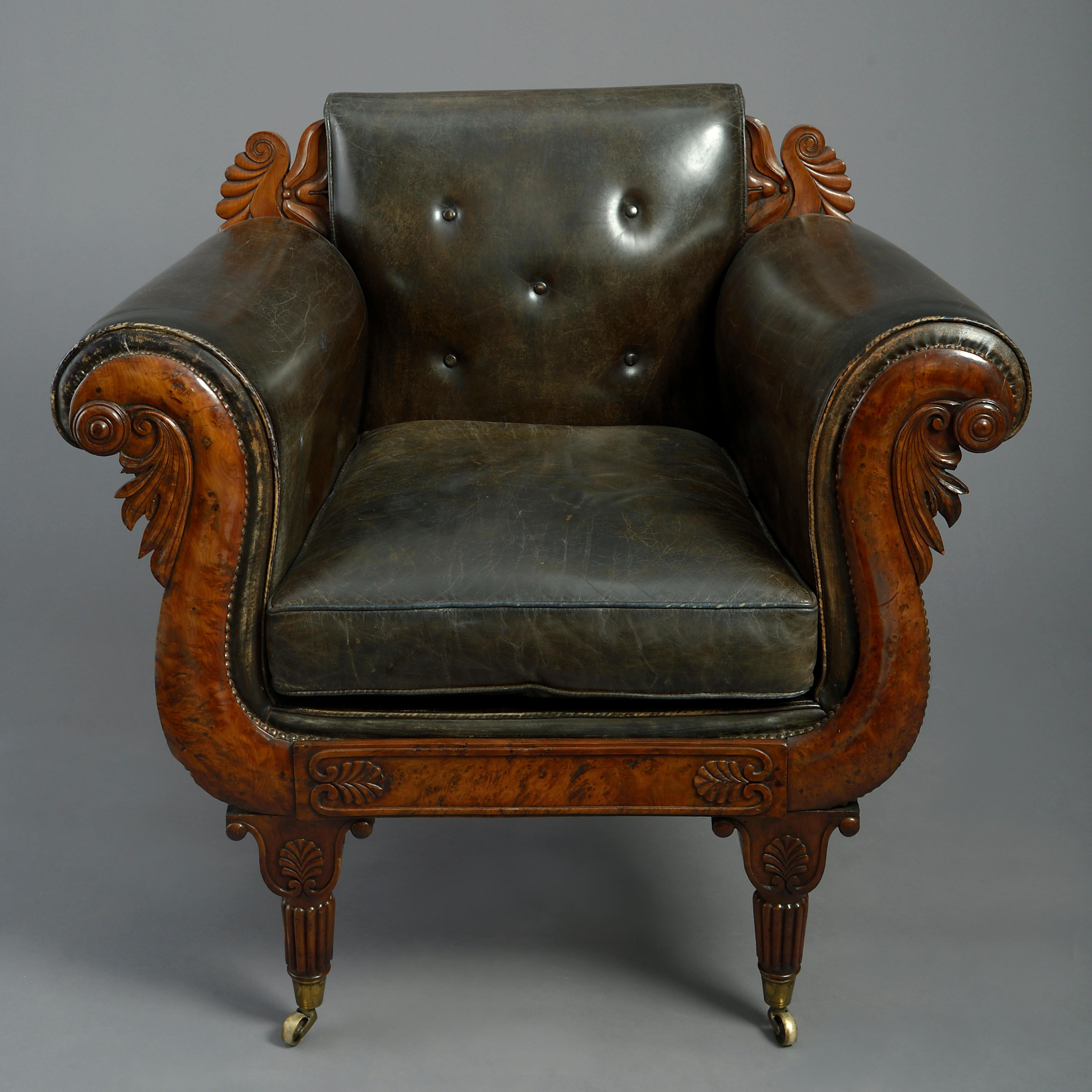 An unusual early nineteenth century Regency Period burr yew wood leather upholstered bergère armchair of generous proportions, the back flanked with carved acroteria, the scrolling arms with stylised acanthus upon a frame of anthemia and raised upon