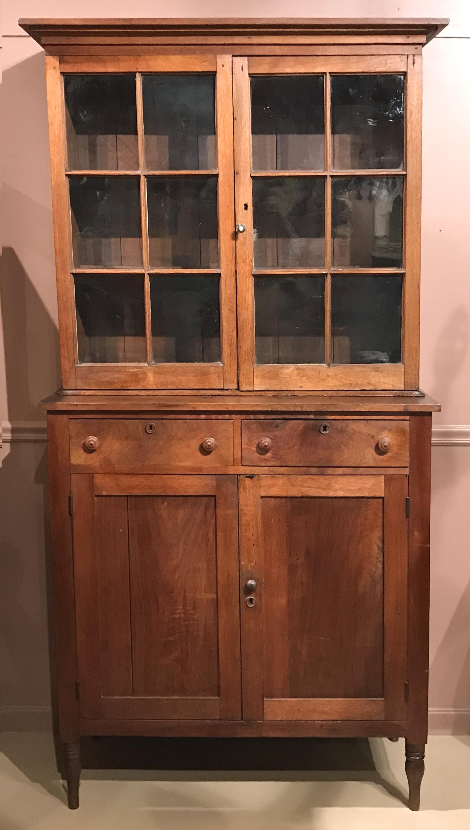 A rare, married step back walnut pie safe cupboard with glazed doors, probably from Virginia, early 19th century. The upper section with cornice molding and two 6 pane glazed doors surmounting a lower case with two drawers over two doors and ends