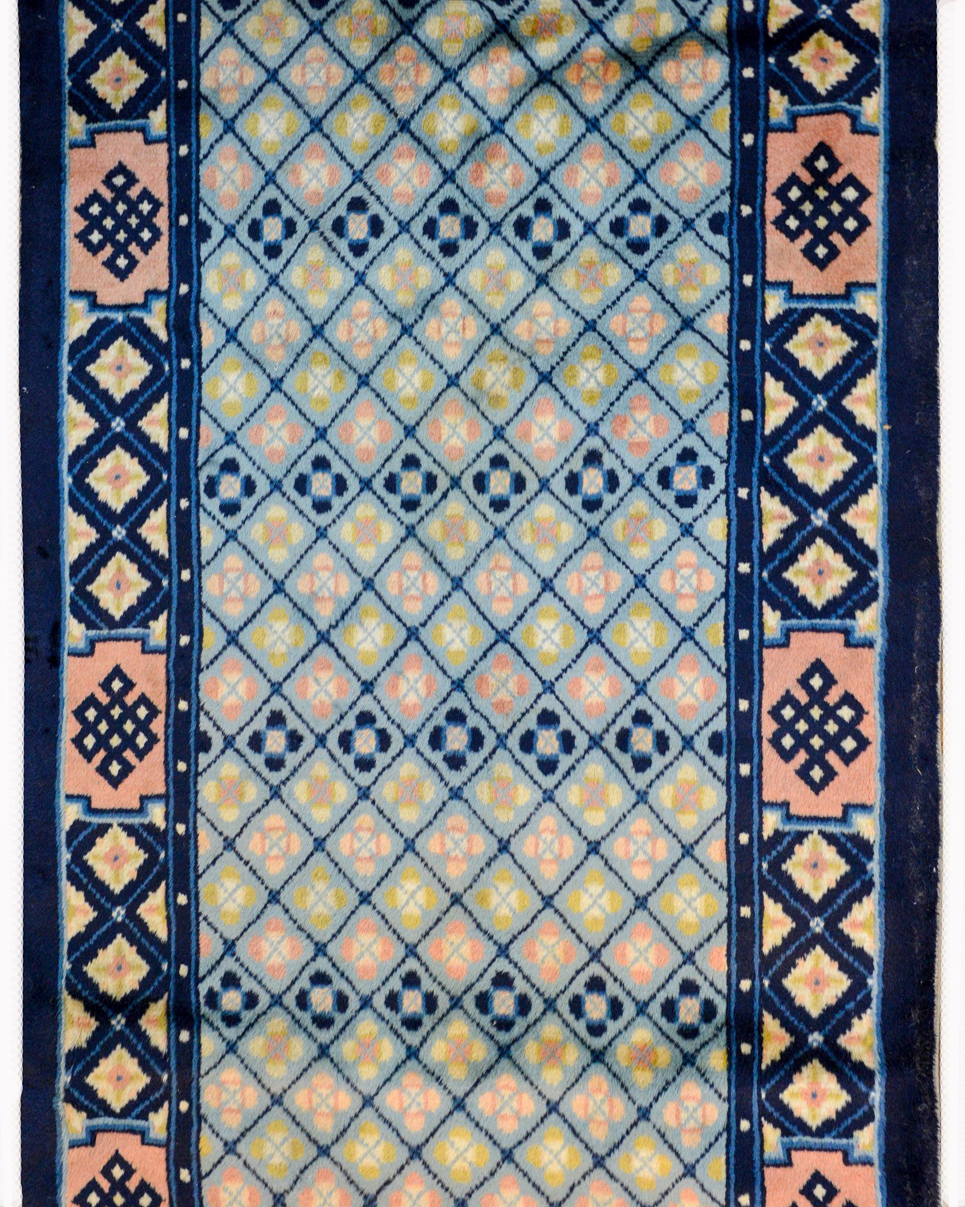 A rare and sweet early 20th century Chinese Peking runner with a field containing an all-over patter of petite flowers woven in pale pinks, greens, and indigos against a light indigo background. The border is unusual too, with a similar petite