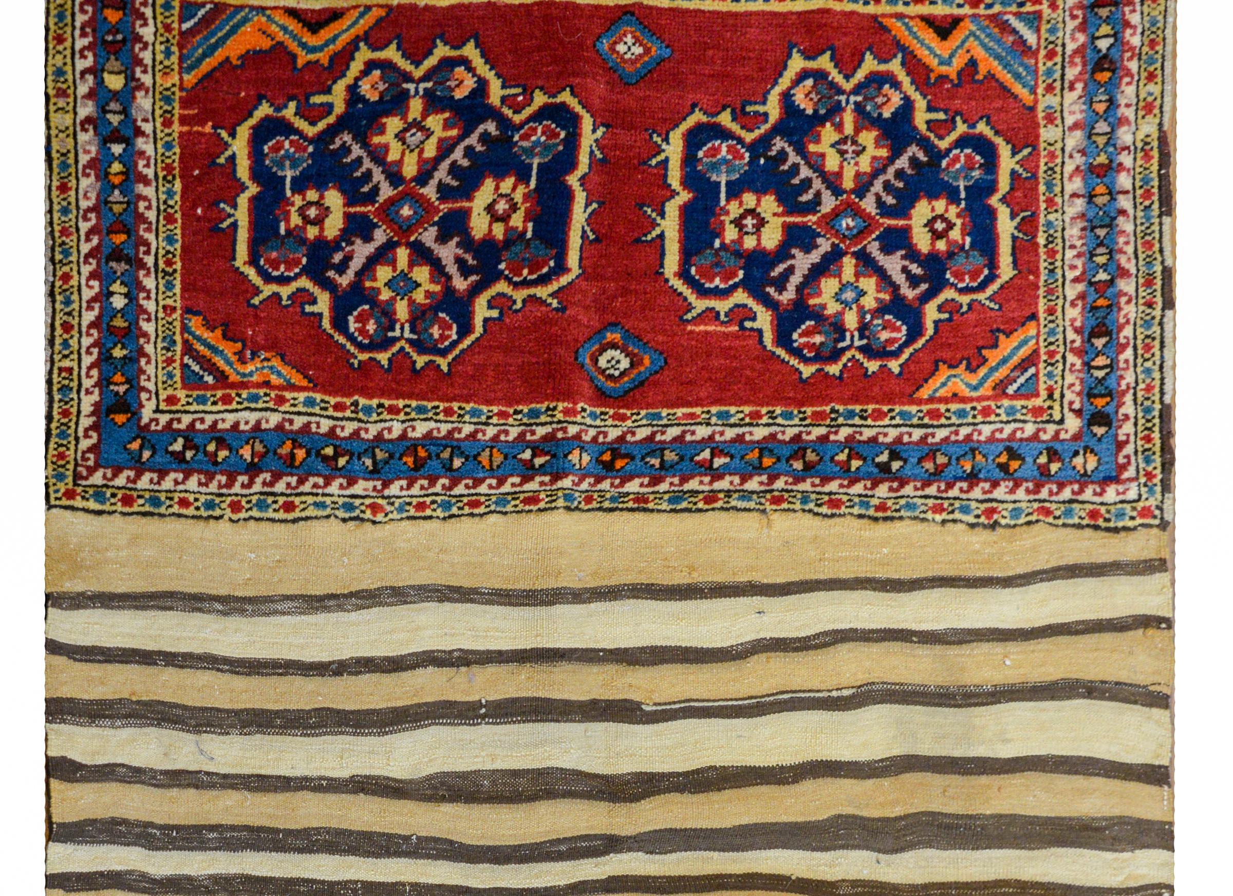 A rare early 20th century Persian Lori horse blanket with a striped flat-weave back with each end having a handwoven pattern containing two medallions with stylized floral patterns on a dark crimson ground.