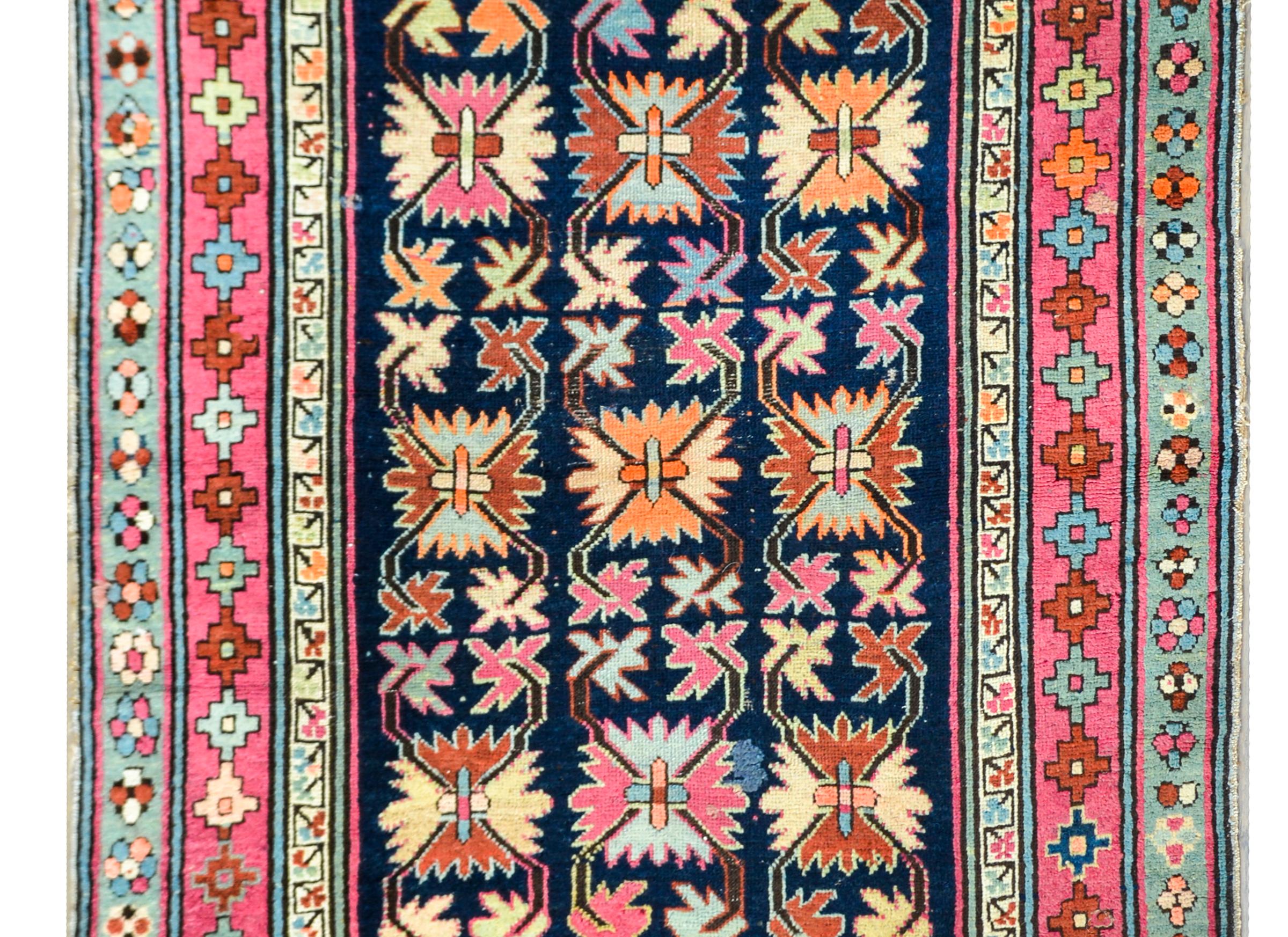 A gorgeous and rare early 20th century Persian Ganjeh prayer rug with the most beautiful stylized floral and leaf pattern woven in wonderful bright pinks, oranges, yellows, blues, fuchsias, and greens, set against a dark indigo background. The