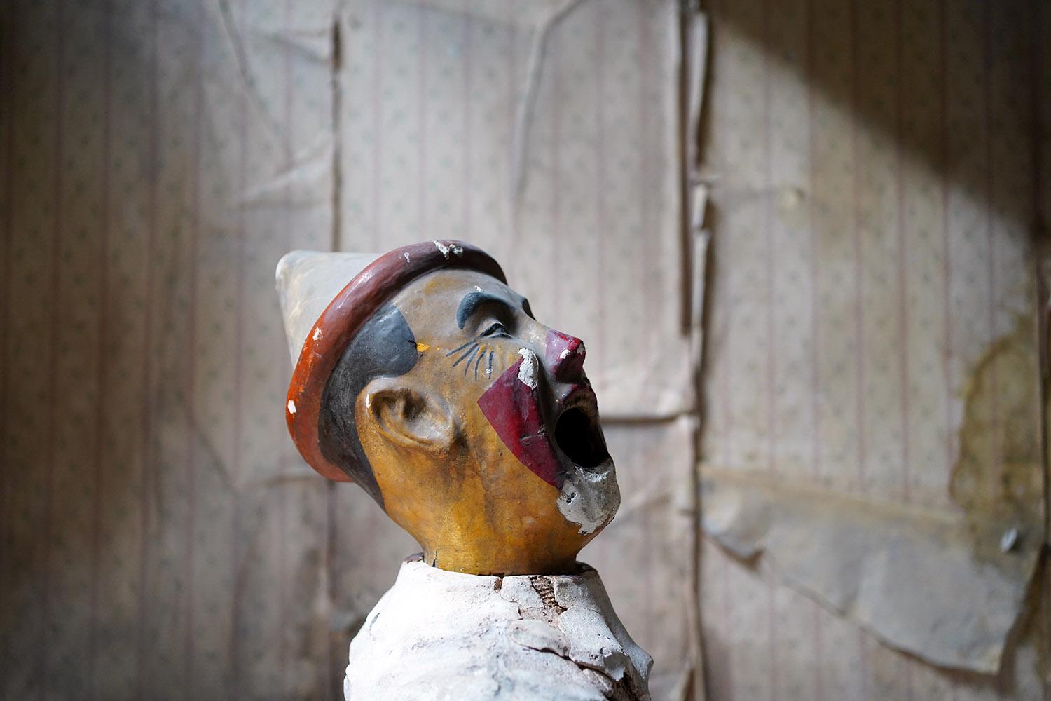 The early fairground or carnival ball game, comprising of a now fragmentary white washed plaster and hessian body with ruffled upper, to cast iron inner piping, to the original painted plaster clowns head with red highlights and conical pierrot hat,