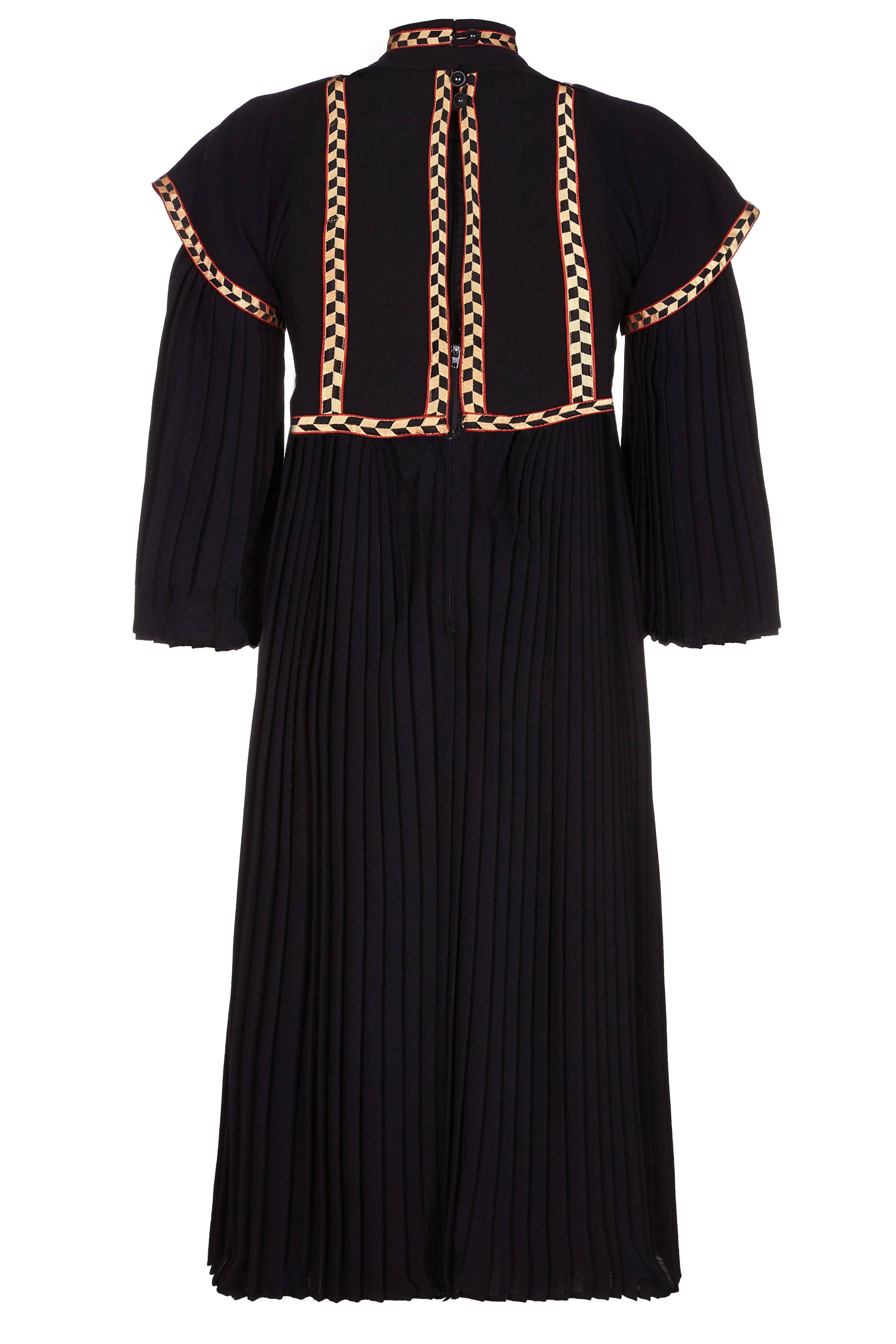 Incredible vintage Bill Gibb black wool renaissance style dress with pleated skirt and sleeves and structured bodice with applique ribbon.  It fastens at the back of the skirt with a zip and has three buttons and loops at the back of the high neck