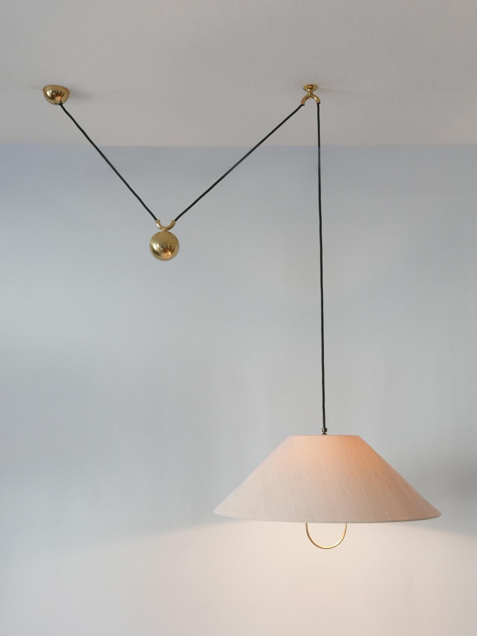 Extremely rare and early counterweight pendant lamp or hanging light. Designed and manufactured by Florian Schulz, Germany, 1960s.

Executed in brass and fabric, the lamp comes with 1 x E27 / E26 Edison screw fit bulb holder, is wired and in working