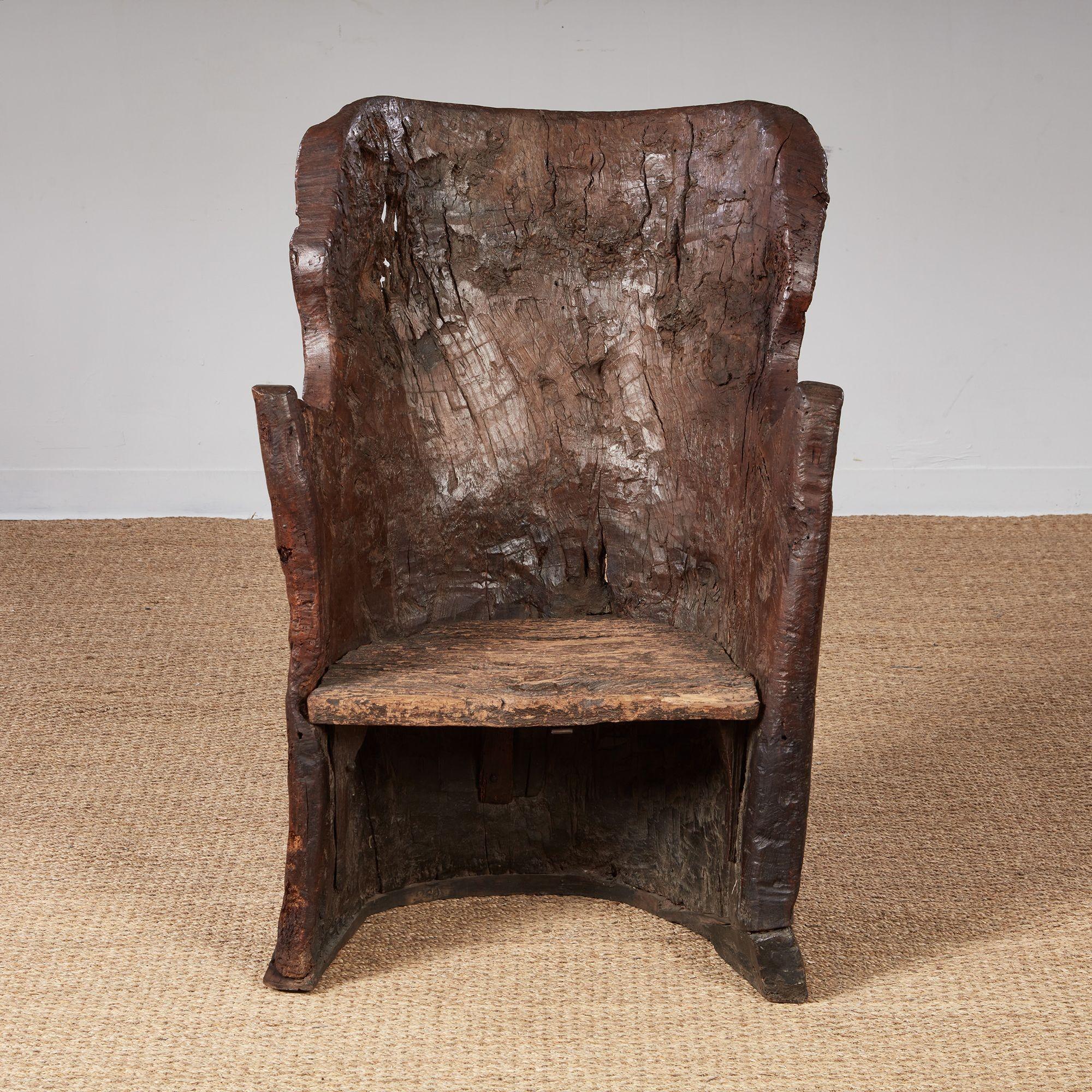 A fine and very rare early 18th century English oak dugout armchair, the generously sized body rough-hewn from a single oak tree trunk, showing adzed and drawn toolmarks and possessing a wonderful organic form.  
Chairs like these were often formed
