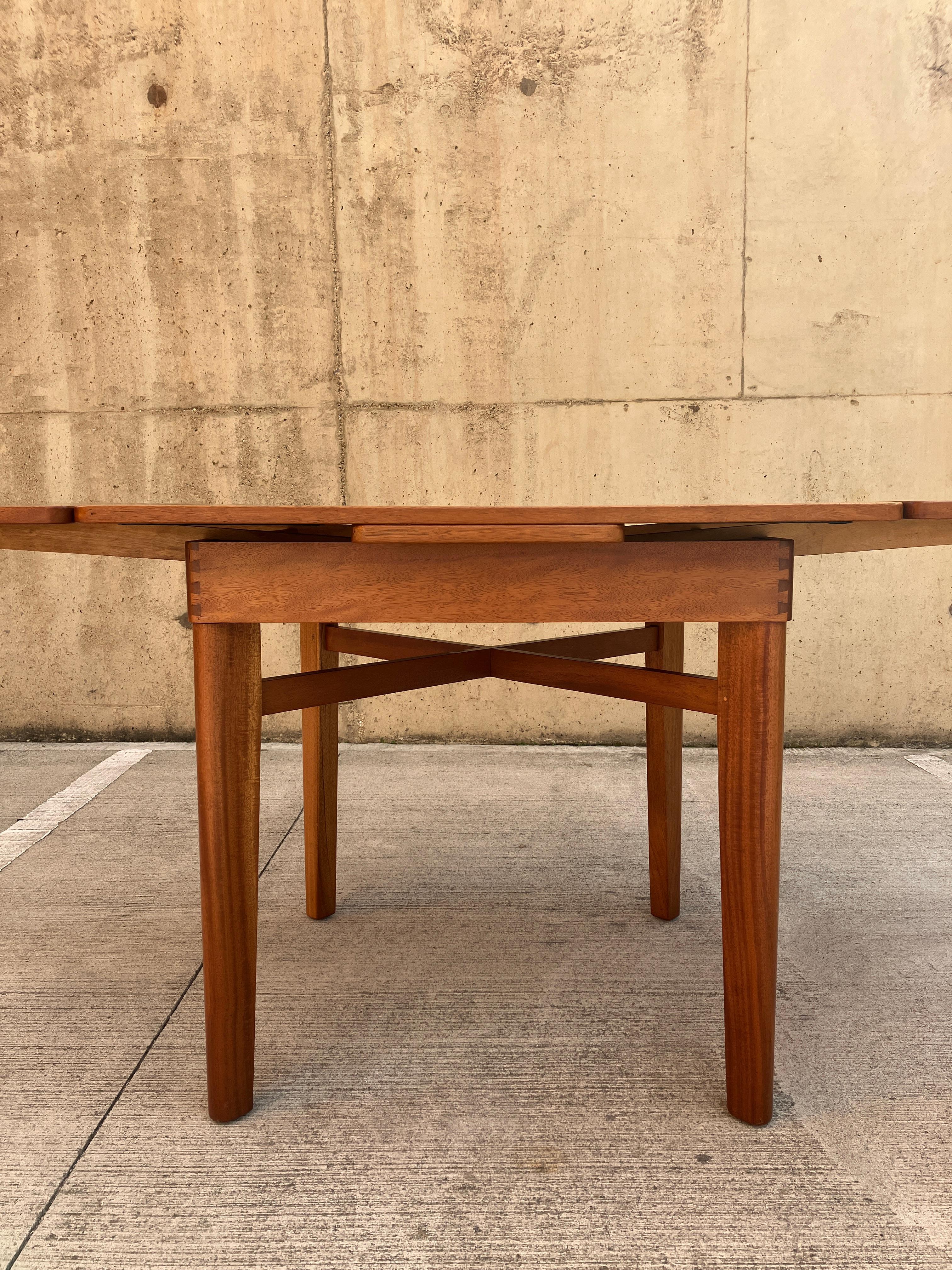 This a very rare, early mid-century dining table designed by Lucian Ercolani for Ercol. The table has plenty of attractive details and is incredibly well crafted. The dining table looks square when closed with a gorgeous cross under the tabletop.