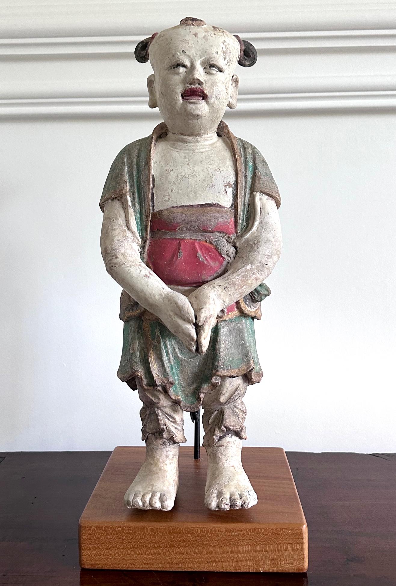 A Korean statue of Dongja made from clay/stucco with wood core and painted with polychrome colors circa 18th century of the Joseon Dynasty. The statue is nicely presented on a custom-made stand with wood base. Dongja figures depict boy attendants of