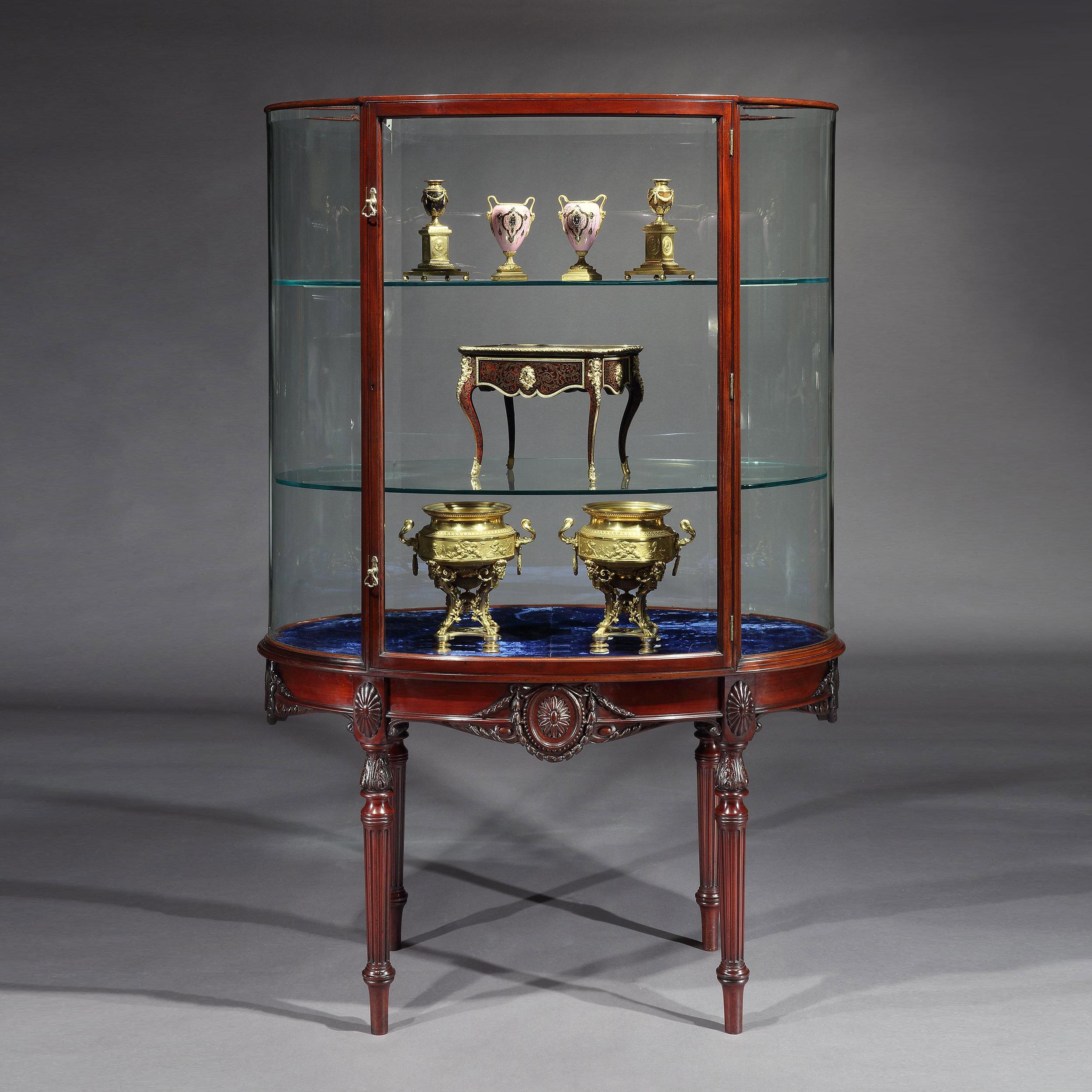 An unusual Edwardian display cabinet
in the Adam manner
By F. Sage & Co

Constructed from solid mahogany, the oval display cabinet supported on turned and reeded legs, its apron decorated in the delicate manner of Robert Adam depicting husking