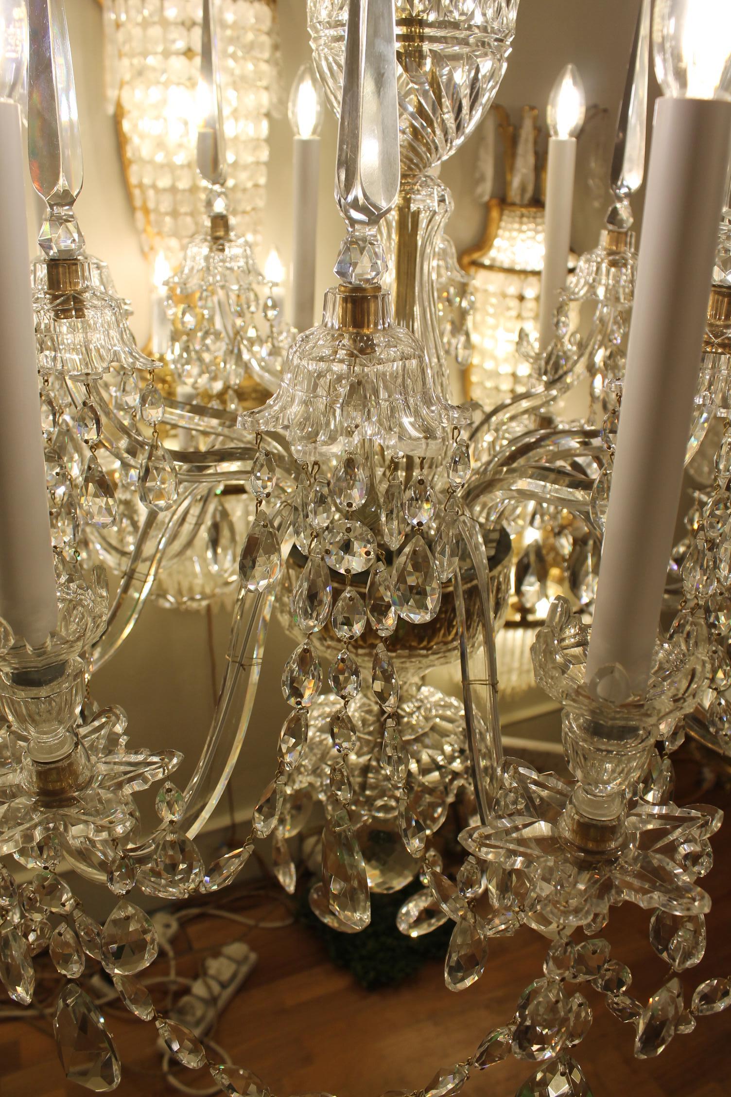 La plaque réceptrice supporte huit bougeoirs avec des coupelles suspendues à enfilement, qui alternent avec des bras supérieurs dotés de pièces en verre suspendues et des flèches triangulaires ; la tige en forme de balustre est dotée de pièces en