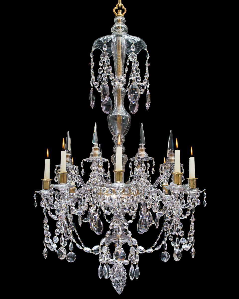 The receiver plate supporting eight candle arms with slip over drop hung drip pans these alternate with upper kick arms these with drop hung canopies and triangular spires, the baluster form stem with corresponding lower and upper drop hung canopies