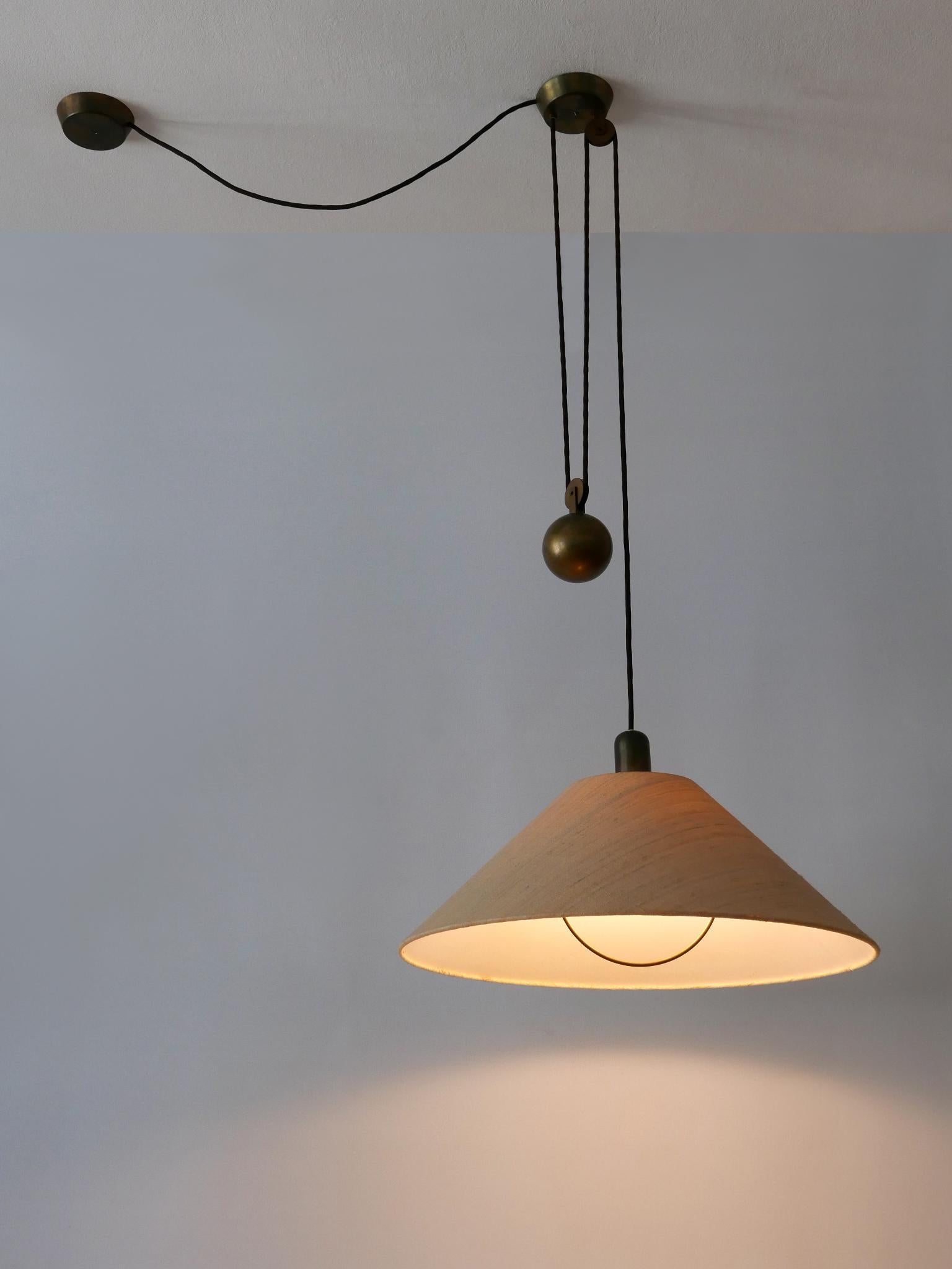 Rare and elegant Mid-Century Modern brass counterweight pendant lamp or hanging light. Designed & manufactured in Germany, 1960s.

Executed in brass and fabric, the lamp comes with 1 x E27 / E26 Edison screw fit bulb socket, is wired and in working