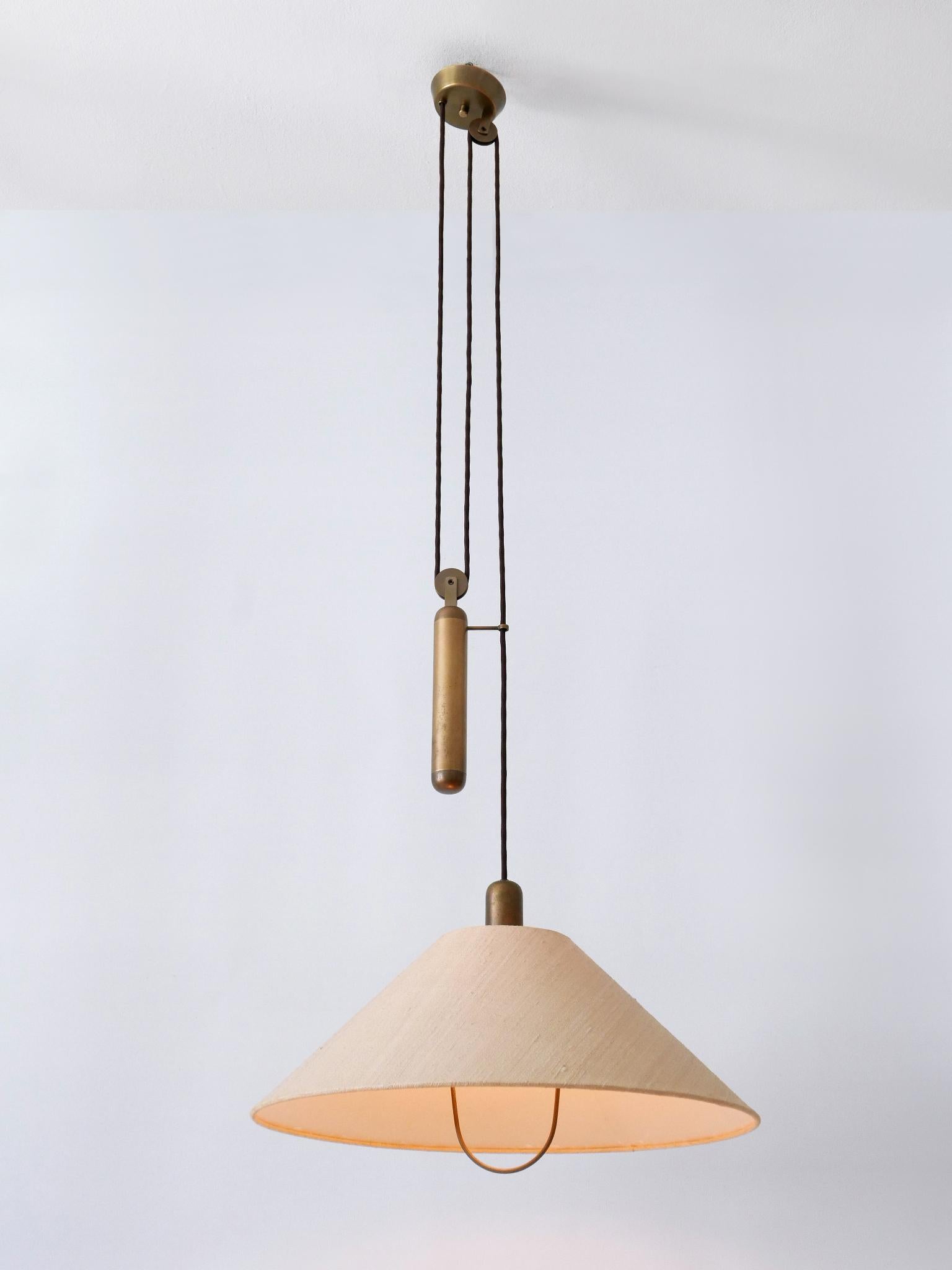 Rare and elegant Mid-Century Modern brass counterweight pendant lamp or hanging light. Designed & manufactured in Germany, 1970s.

Executed in brass and fabric, the lamp comes with 1 x E27 / E26 Edison screw fit bulb socket, is wired and in working