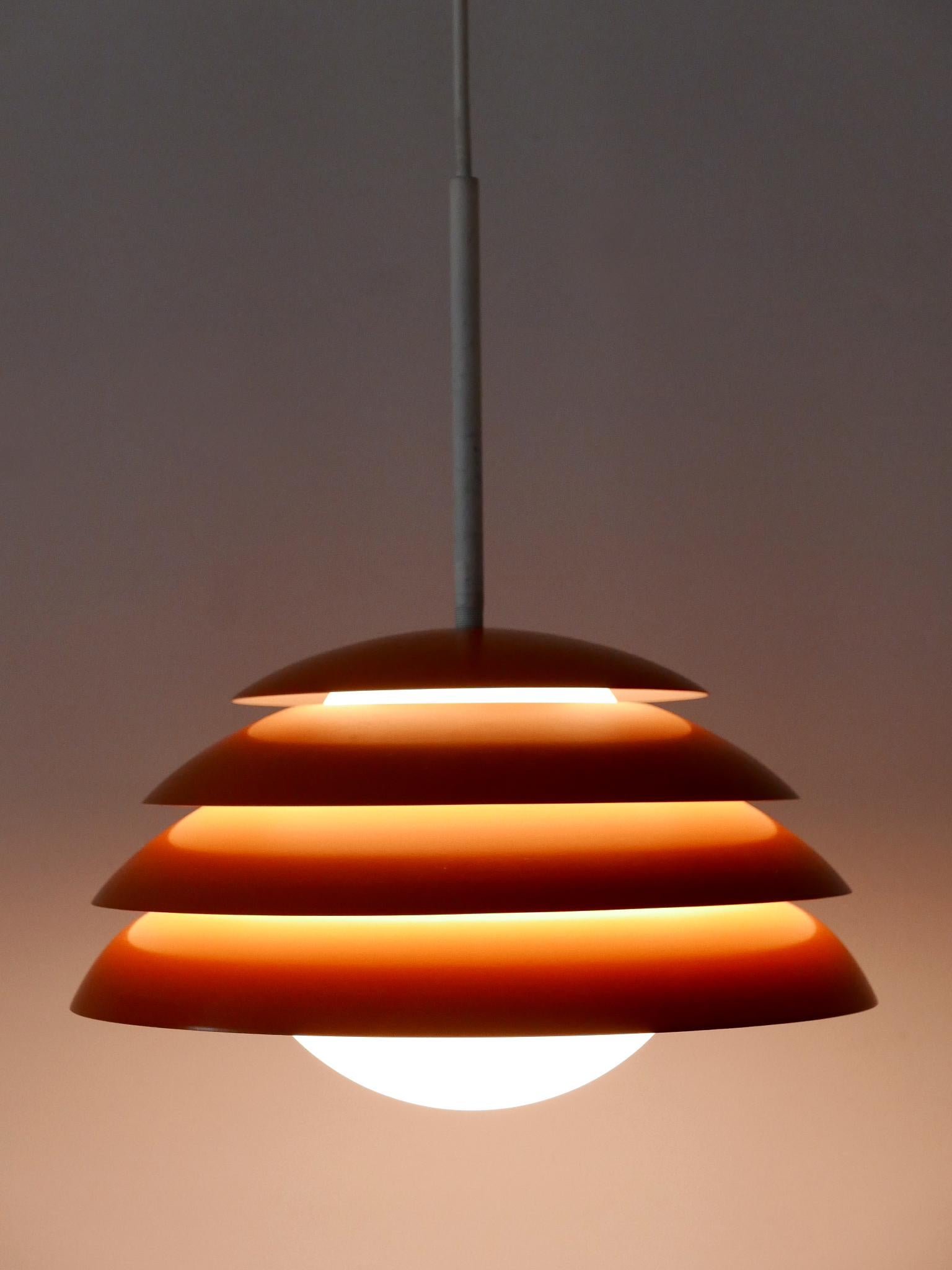 Preciosa y muy decorativa lámpara colgante o lámpara colgante Moderna de Mediados de Siglo. Diseñado y fabricado en Alemania, década de 1960.

Realizada en aluminio esmaltado naranja y cristal opalino, la lámpara colgante viene con 1 casquillo de