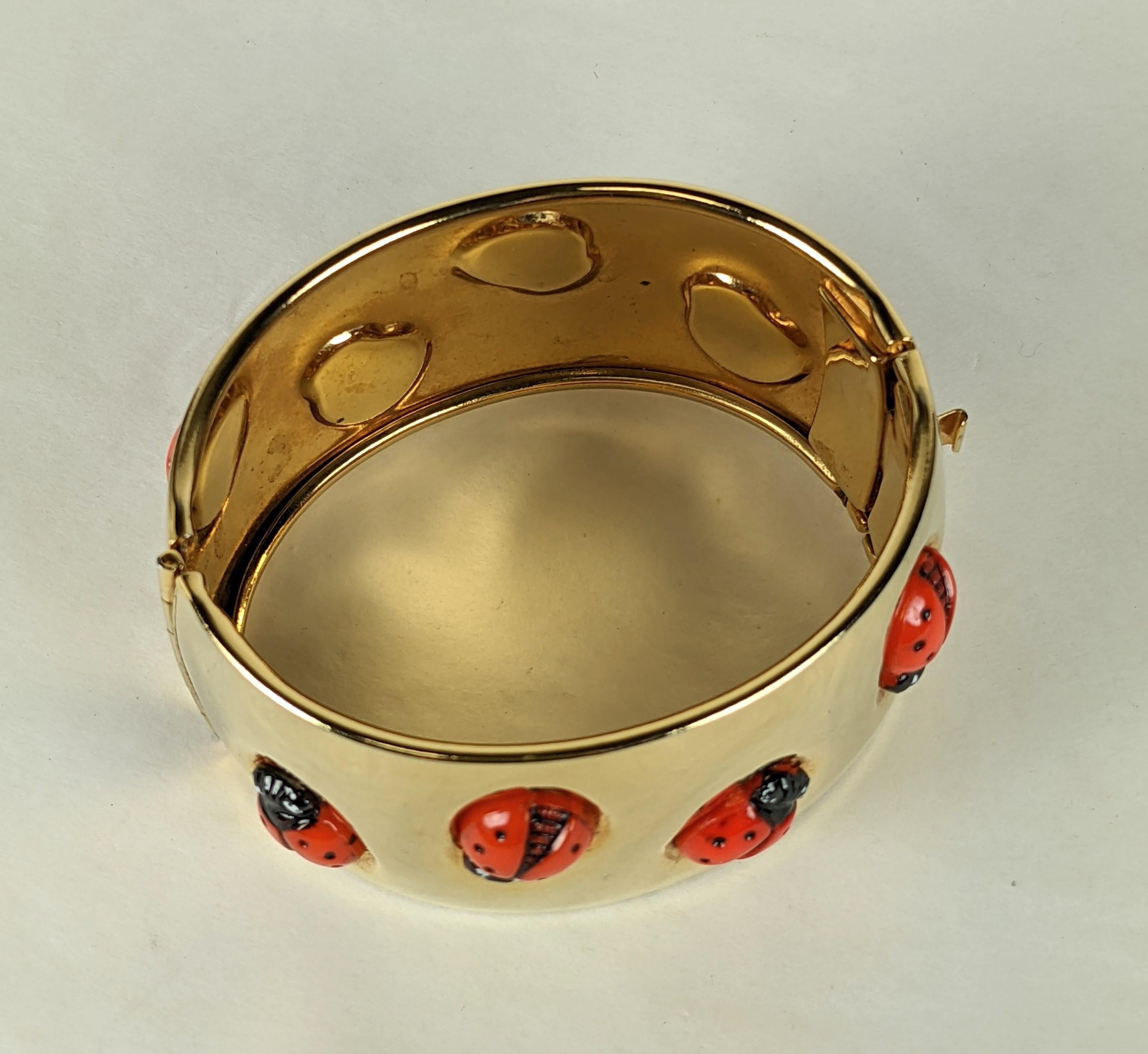 Elsa Schiaparelli surrealist lady bug cuff bracelet. Of gilt plate metal the bombayed hinged cuffs inset with red, orange molded pate de verre glass lady bugs, partially painted in black cold enamel. The lady bug symbolizes good luck and good