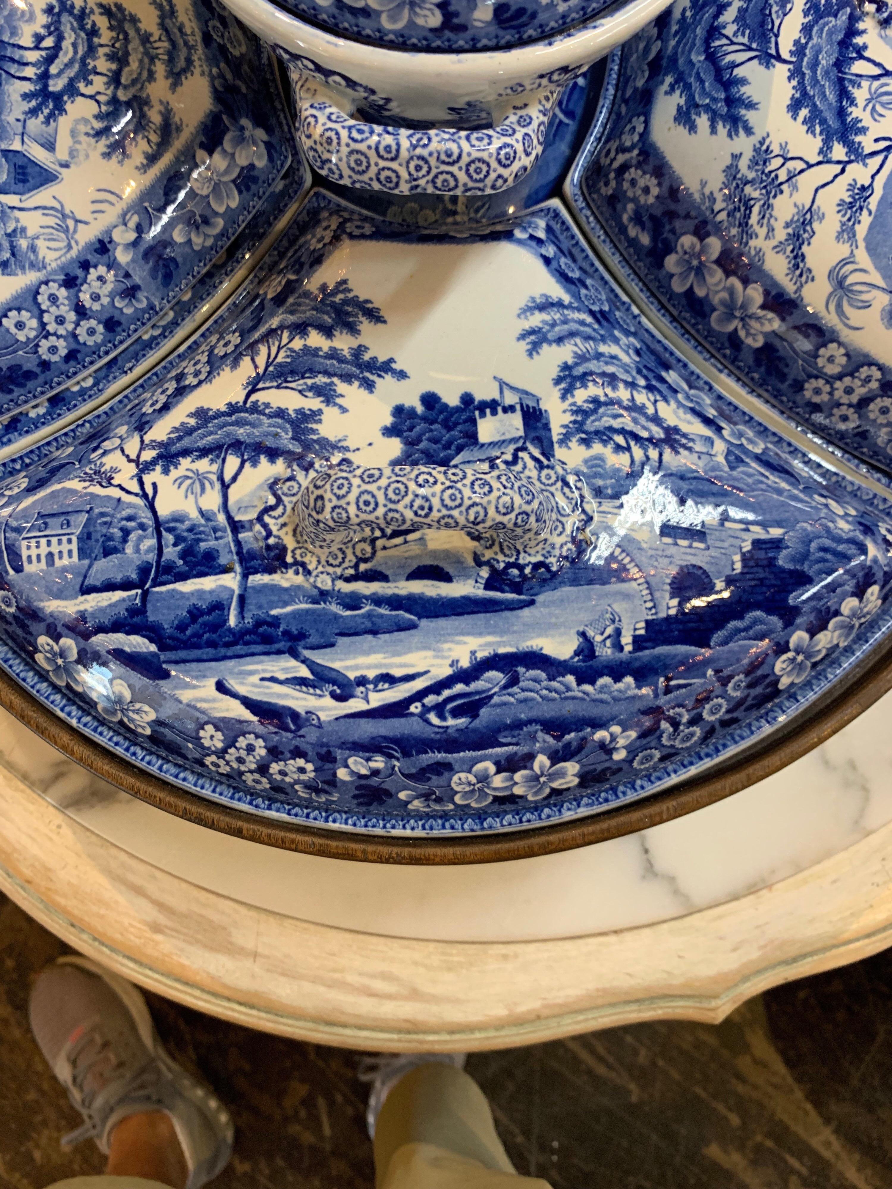 Very unique English porcelain Lazy Susan in nice blue and white pattern with Asian images. There are 4 serving sections on the bottom and the top section contains small cordial glasses. This piece is beautiful for a centerpiece, but functional as