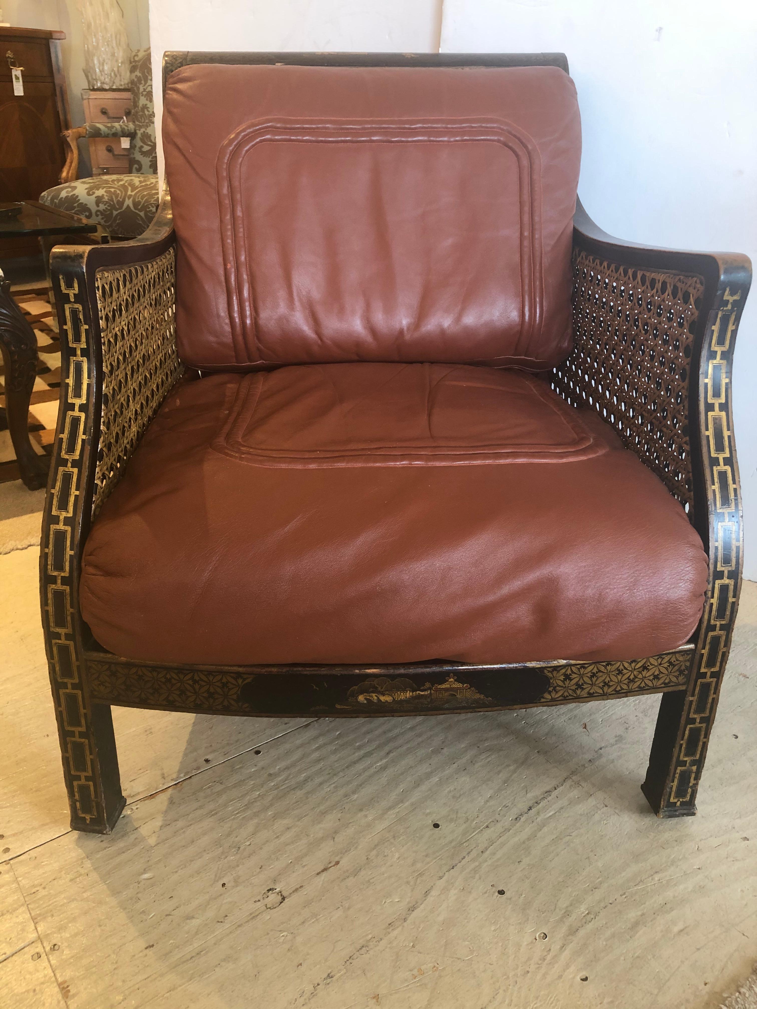 Marvelous luxurious Regency style club or armchair having black and gold chinoiserie frame, double caned body in amazing condition, and two down filled cognac colored soft kid leather cushions. You never see a chair like this. Sure to make you swoon.