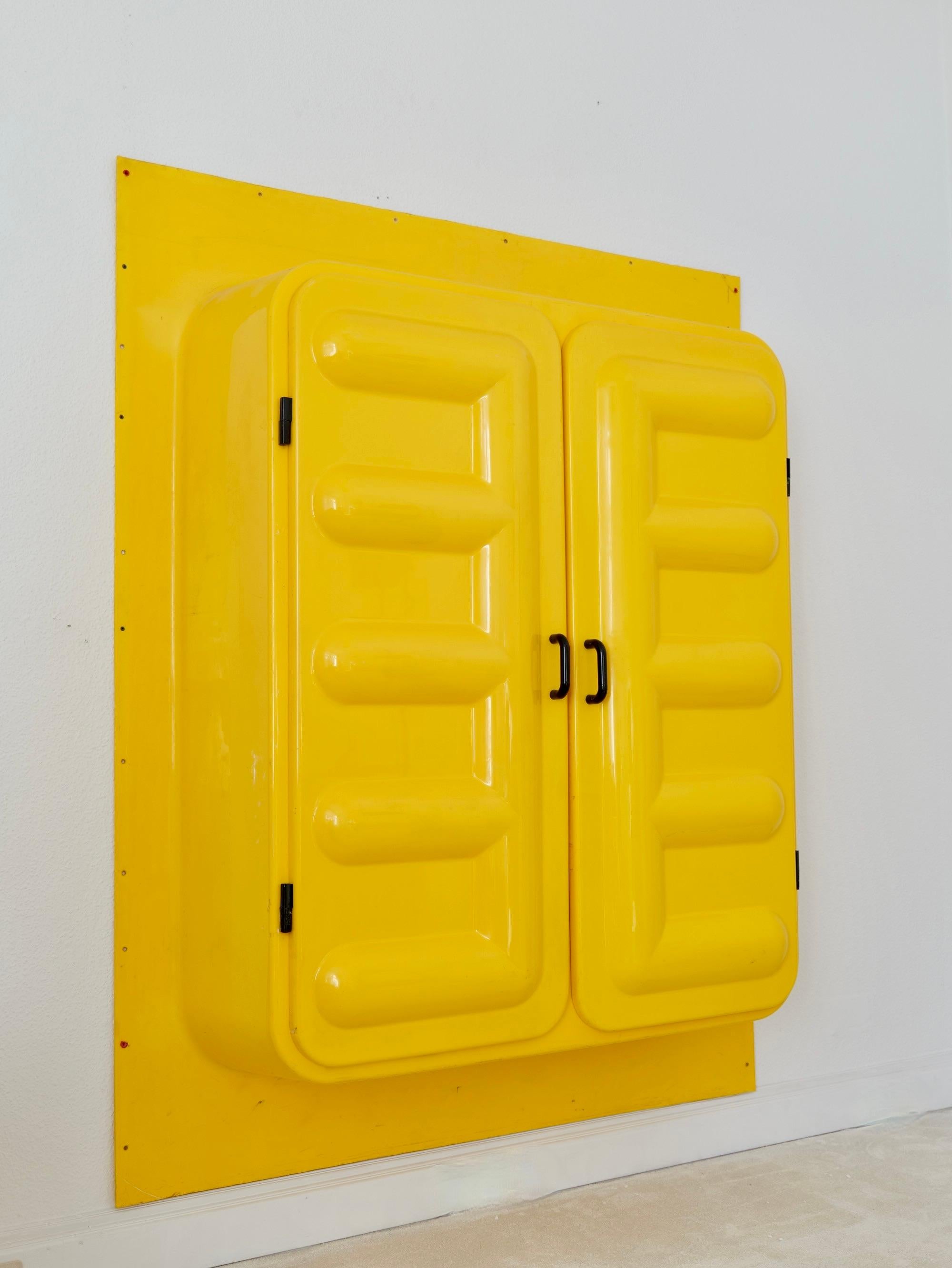 À une époque où le plastique était encore un matériau nouveau, les industriels français ont voulu montrer ce qu'il était possible de faire avec le plastique. À cette fin, une armoire murale surdimensionnée a été produite pour le salon afin d'étonner