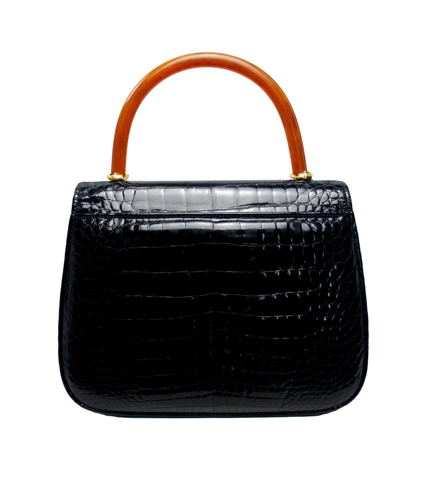 A rare vintage GUCCI exotic skin handbag
Lucite top handle
Shiny black alligator skin
A very special piece in excellent overall condition
One inner pocket with zip and GUCCI crest
Shiny light golden hardware
Stamp 