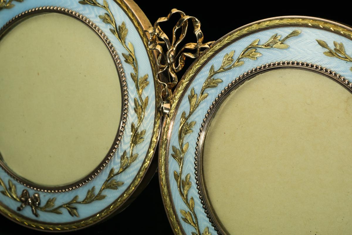 A rare, museum quality, highly important FABERGE two-color gold and guilloche enamel double picture frame.
The frame was made in St. Petersburg between 1908 and 1917.
Two rose gold round frames are joined together with a gold bow. The frames are