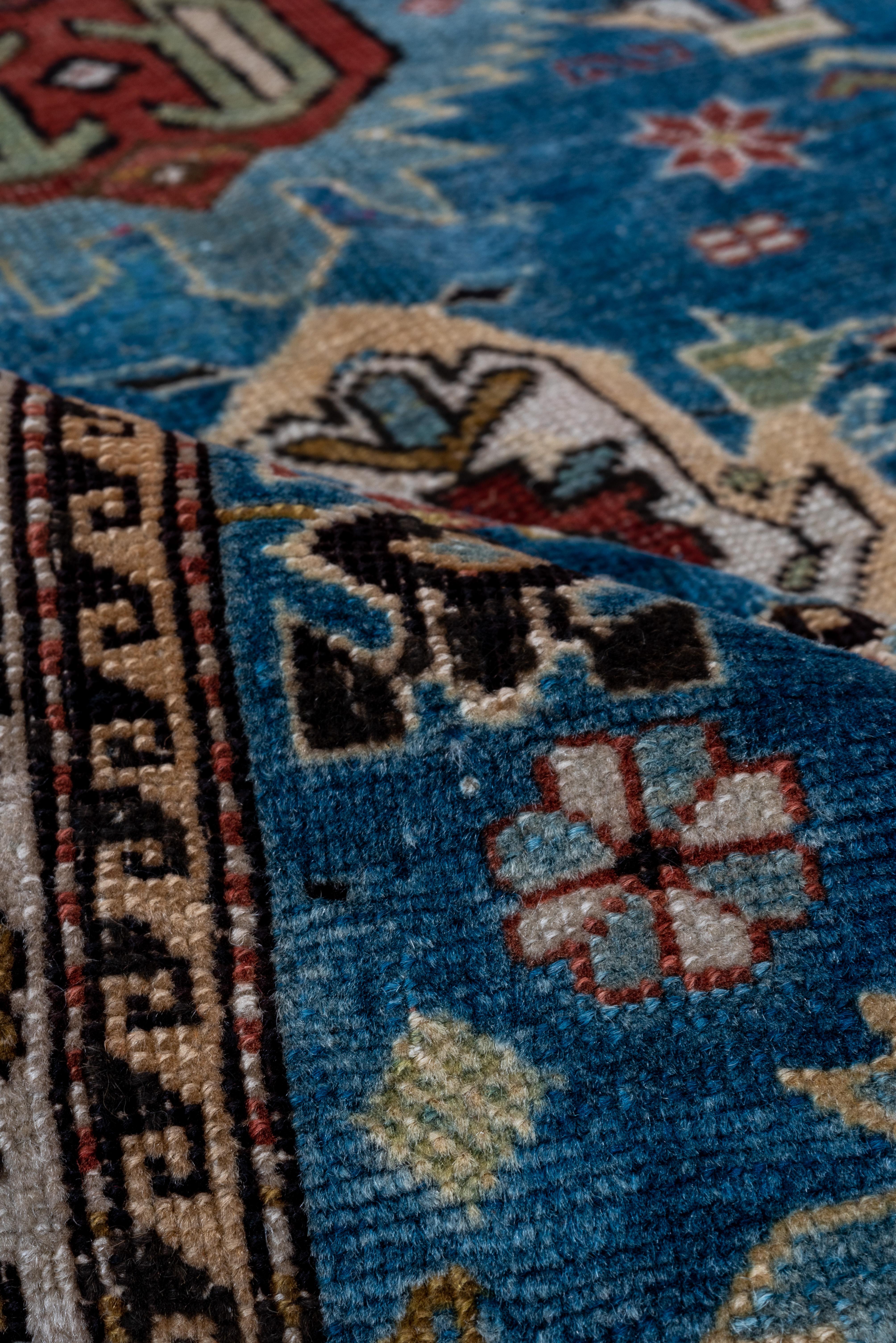 This extremely finely knotted East Caucasian scatter shows a luminous sapphire blue field with a broken three column design of sky blue palmettes, and teal, red coral and ecru details. Various rosettes and abstract flowers actively fill the field.