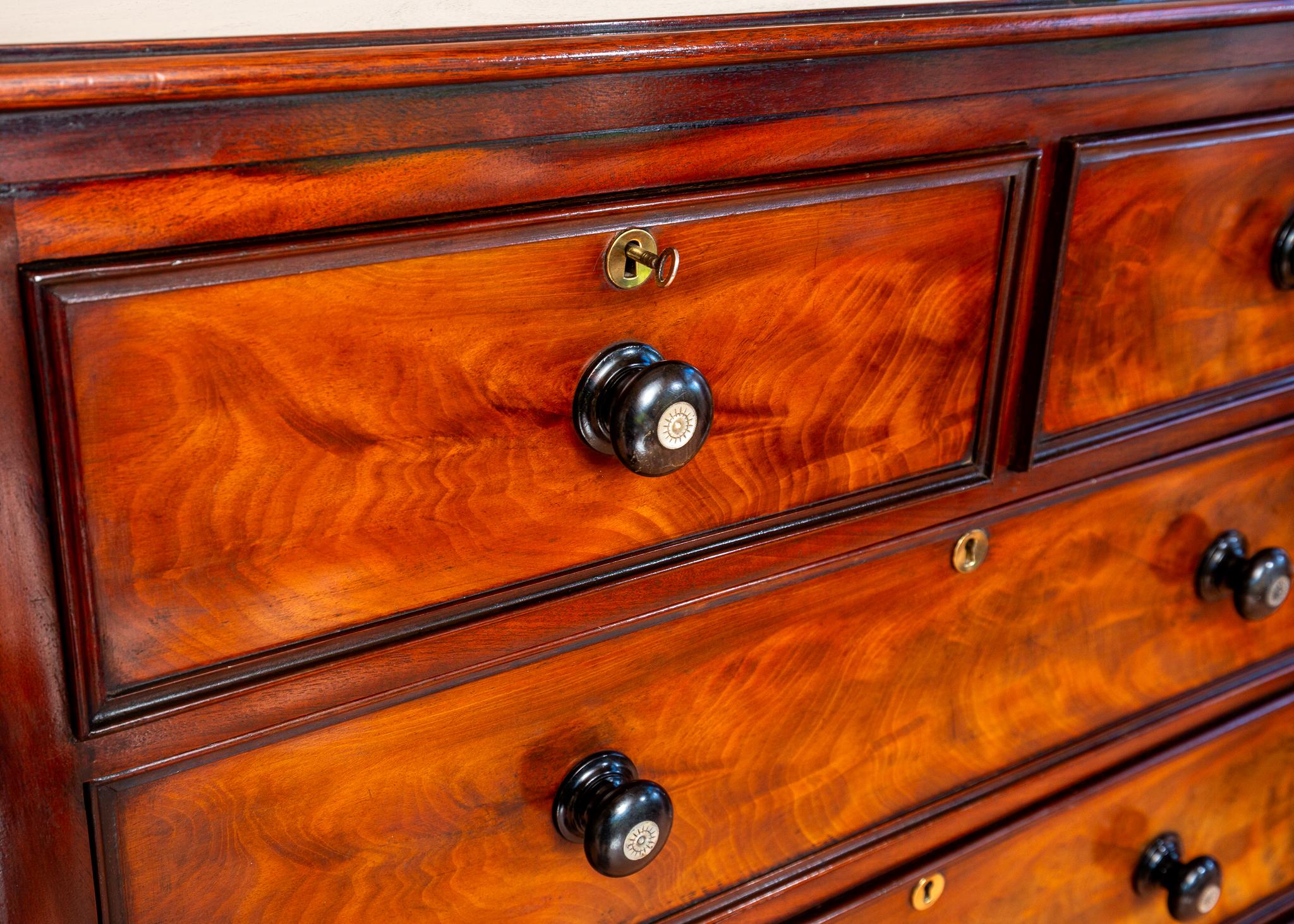 A gorgeous and extremely rare 19th Century tall flame mahogany chest of 7 drawers in lovely condition.  Likely hailing from early Victorian England, circa 1840, as well as being stunning and excellently crafted, this exceptional chest of drawers has