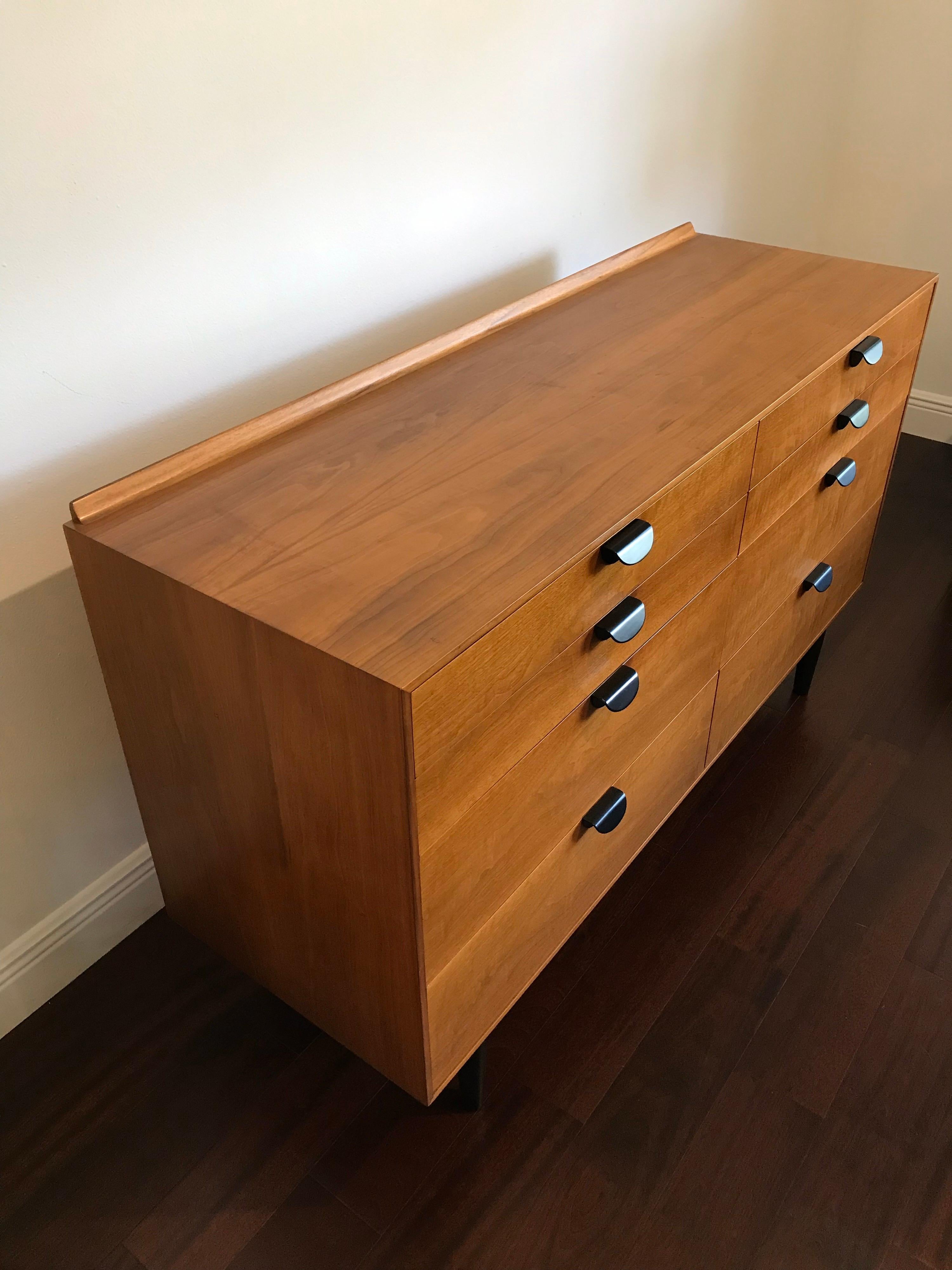 Rare dresser by Finn Juhl for Baker furniture. This dresser features a natural tone walnut case, with a black base and pulls. Restored. 

Note- overall height, lip included, is 33”. Surface height is 32.25”.