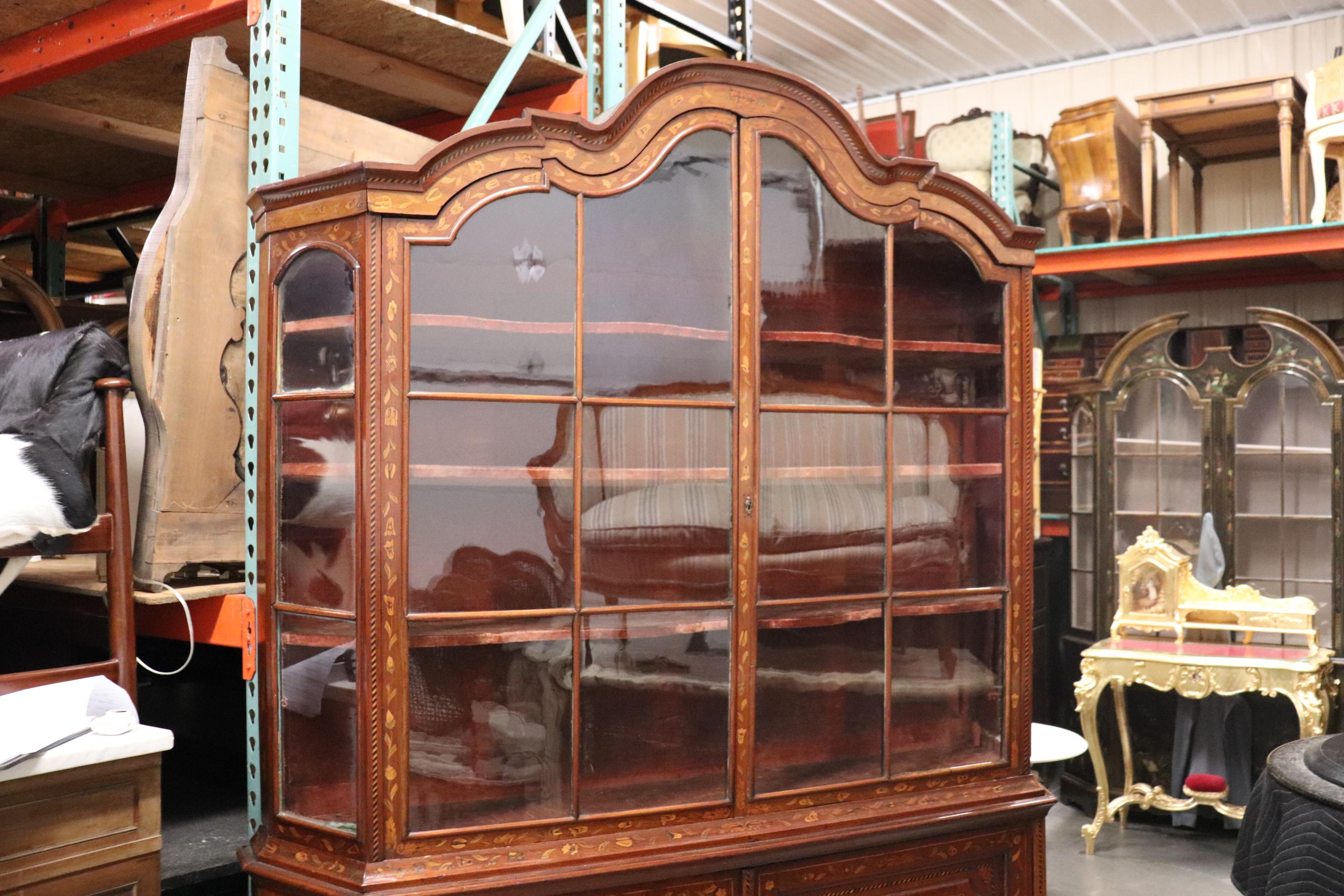 This is a very rare antique Flemish or Dutch marquetry cabinetv with red velvet lined interior, wavy glass and even lighted inside. The lighting is from the early to middle 1900s era so we would recommend replacing it. The case is absolutely