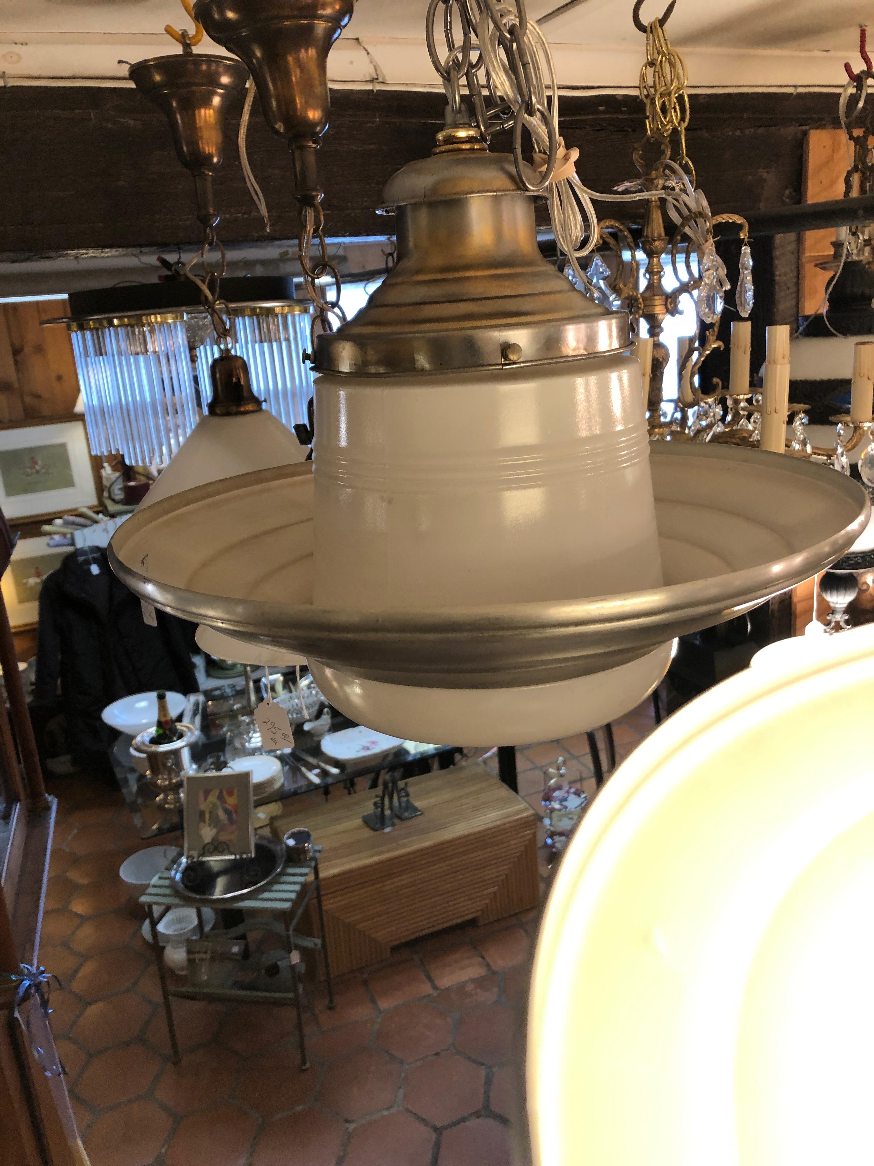 A super cool authentic midcentury industrial pendant fixture having milk glass and clear glass concentric circle base and aluminum body. Note: A pair is available.
Measures: 32