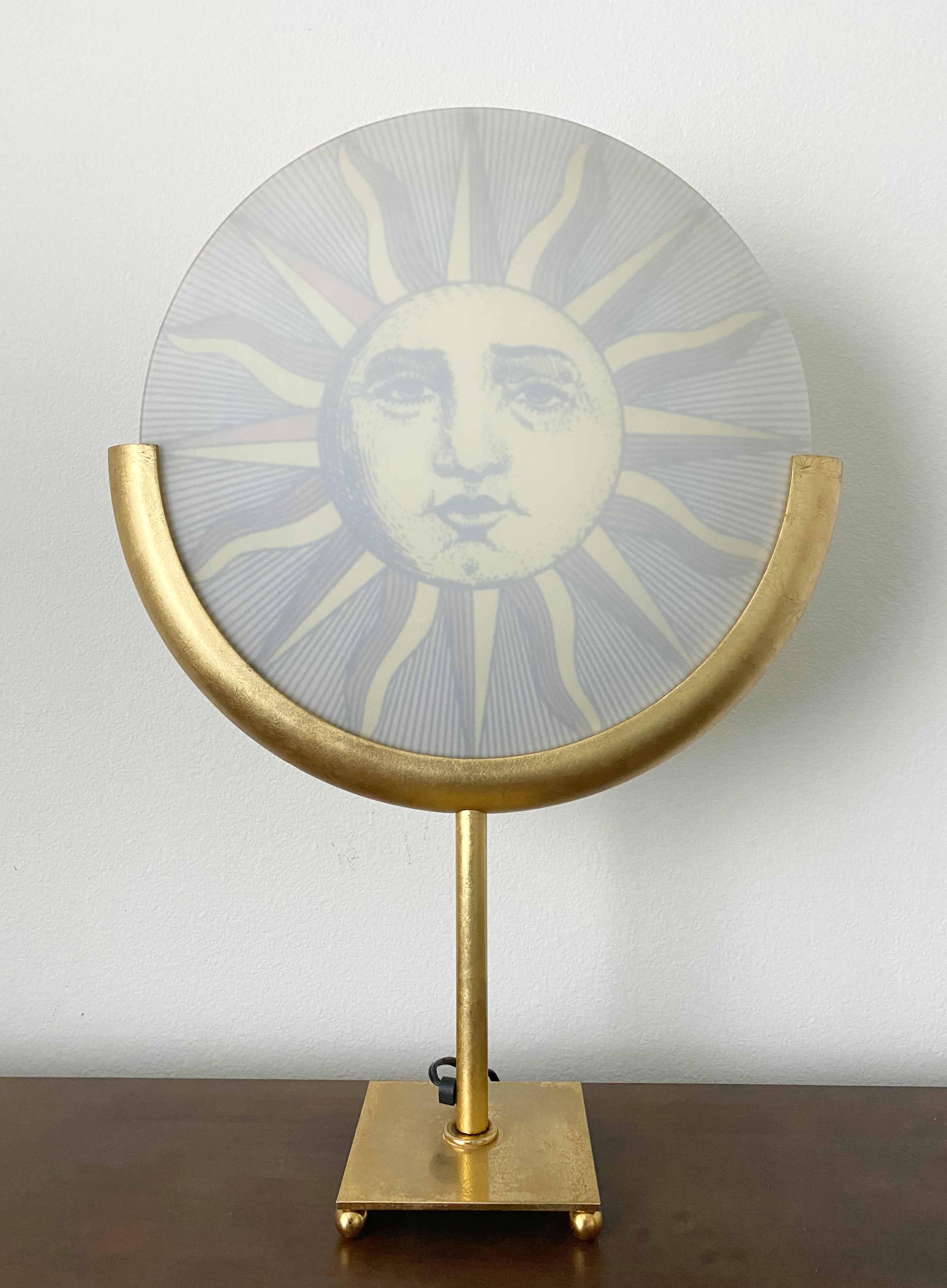 Vintage Italian table lamp in gilt wood and metal with reverse painted depictions of the Sun and Moon, designed by Piero Fornasetti, manufactured by Antonangelli Illuminazione in Milan Italy in the 1980s
Original labels on the lamp holder and the