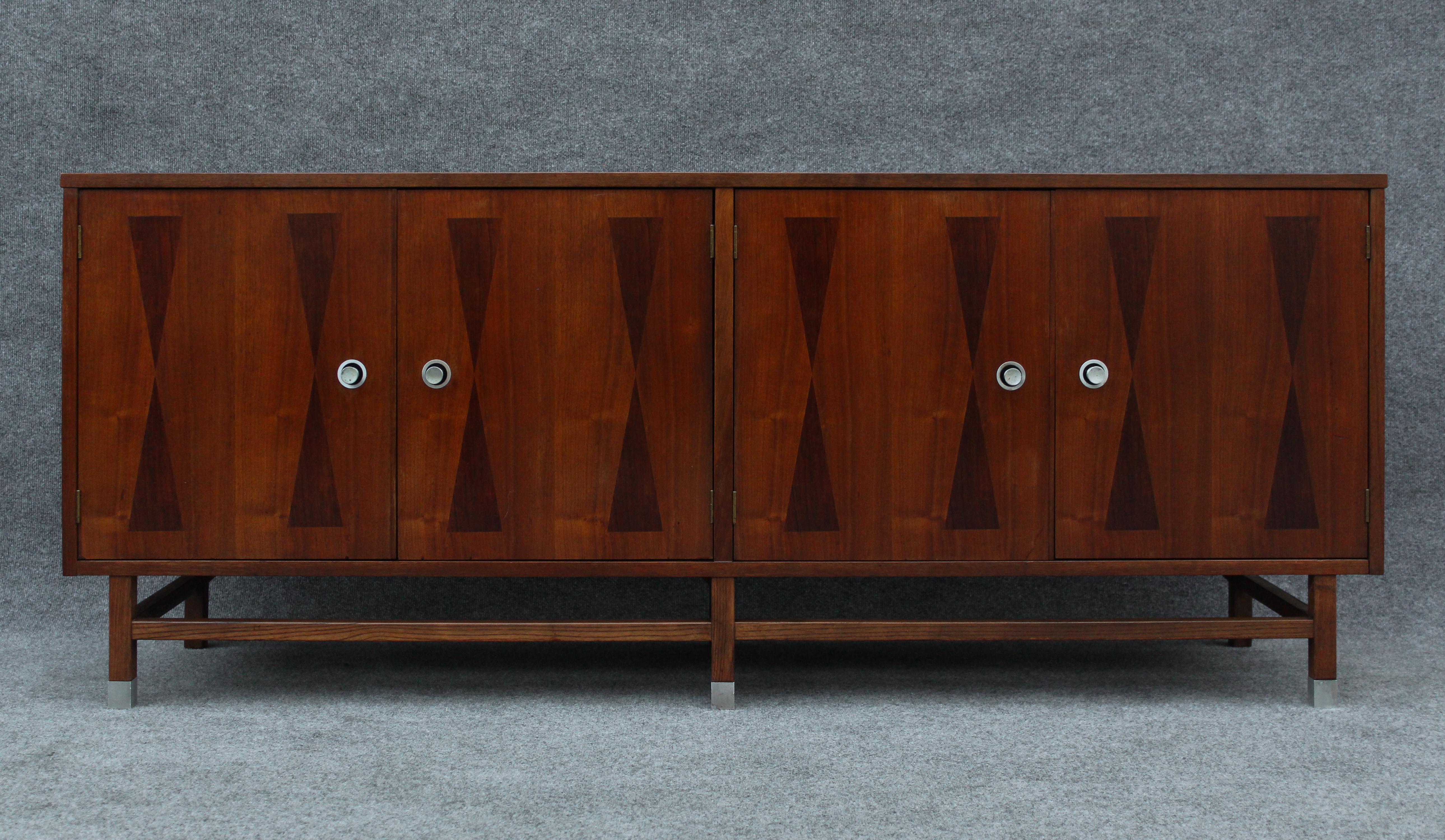 Made in the 1970s by luxury furniture manufacturer Stanley, this rare cabinet features excellent materials and character. Made mostly of walnut, it has four doors which open to reveal three large drawers on the right and two large shelves on the