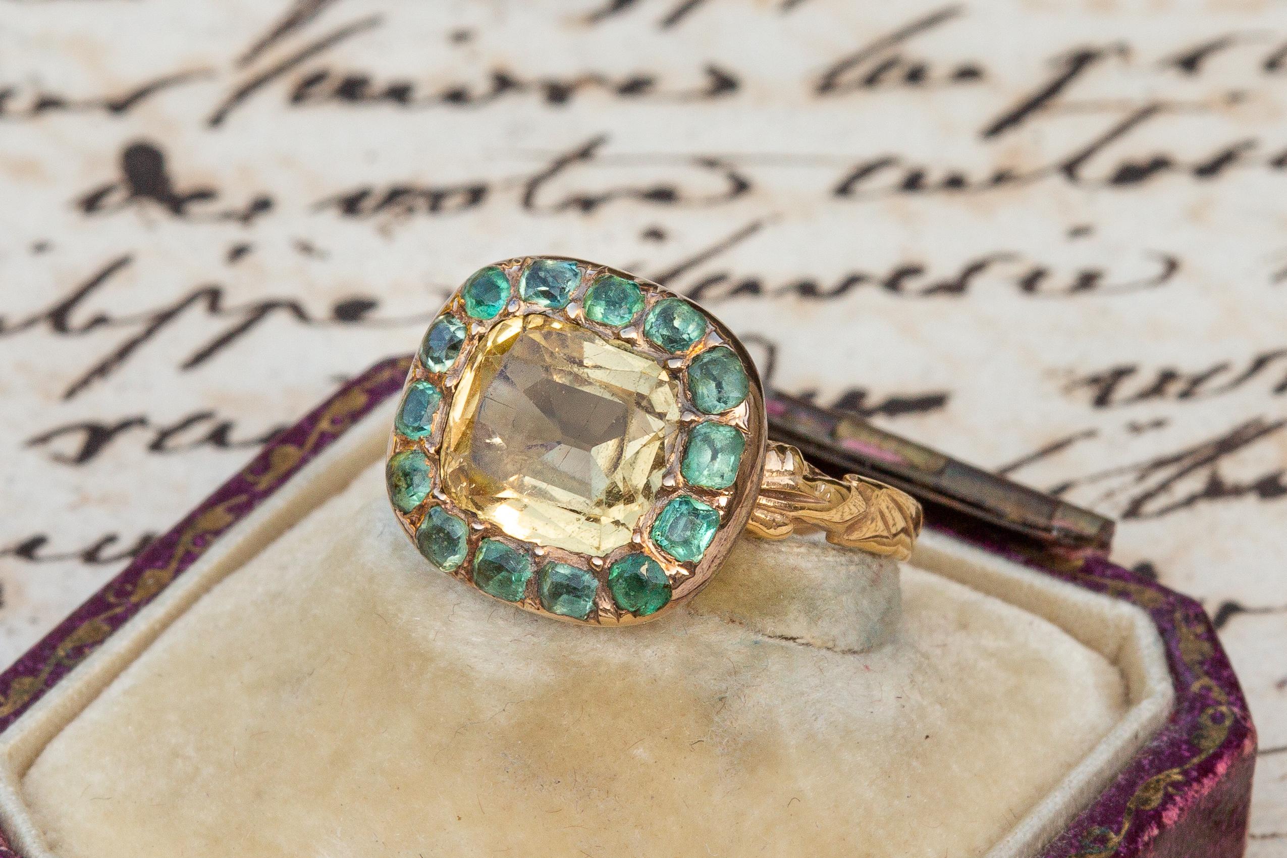 A stunning late 18th century cluster ring set with a 2.12ct pale yellow citrine. It is surrounded by a halo of 14 cushion cut emeralds set in pinch collet settings. The detail of the ring is typical of French craftsmanship of the period; a shank