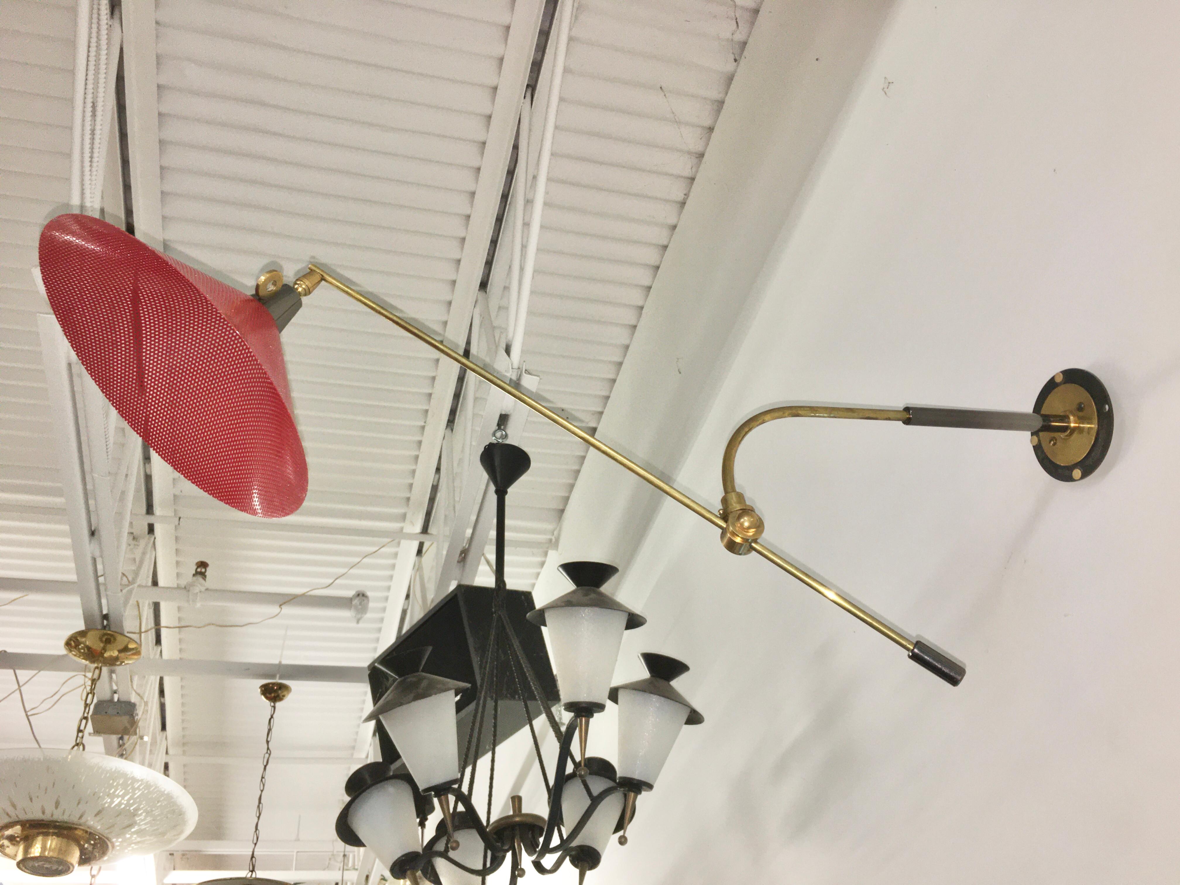 Rare French 1950's swing arm wall lamp with red enameled perforated metal shade, gunmetal fittings and solid brass structure.  Can be positioned with L shaped wall bracket facing up or down.
Rewired for USA. Takes a single candelabra size bulb up to