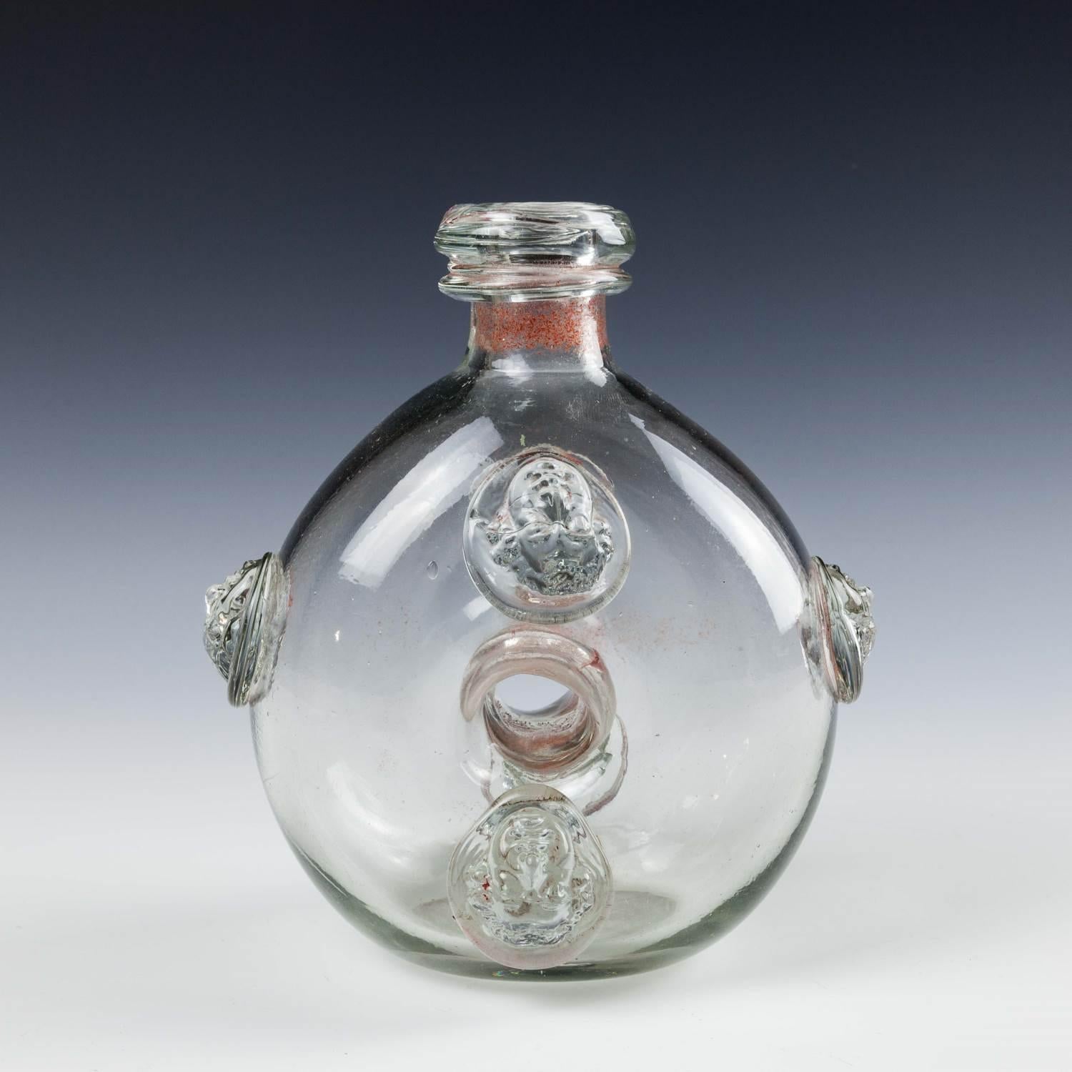 Heading : A very rare French annular flask 1715-1774
Period : Louis XV
Date : 1715-1774
Origin : Most probably Orleans
Colour : Clear. There are iron oxine inclusions within the neck pierces centre
Pontil : Snapped pontil scar on base
Glass Type :