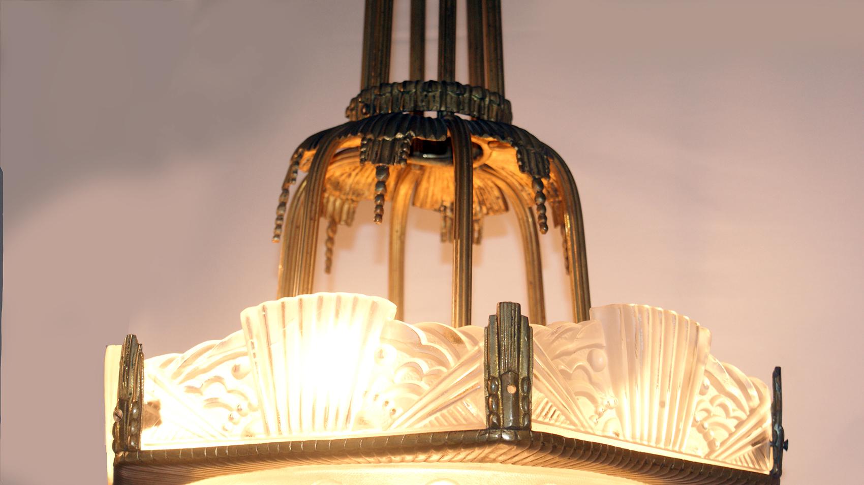 A stunning French Art Deco chandelier by Georges Leleu. France early 1930s. It’s a typical French art deco chandelier, having a round center coupe and six clear frosted glass panels with geometric motif design. Held by a matching gorgeous original