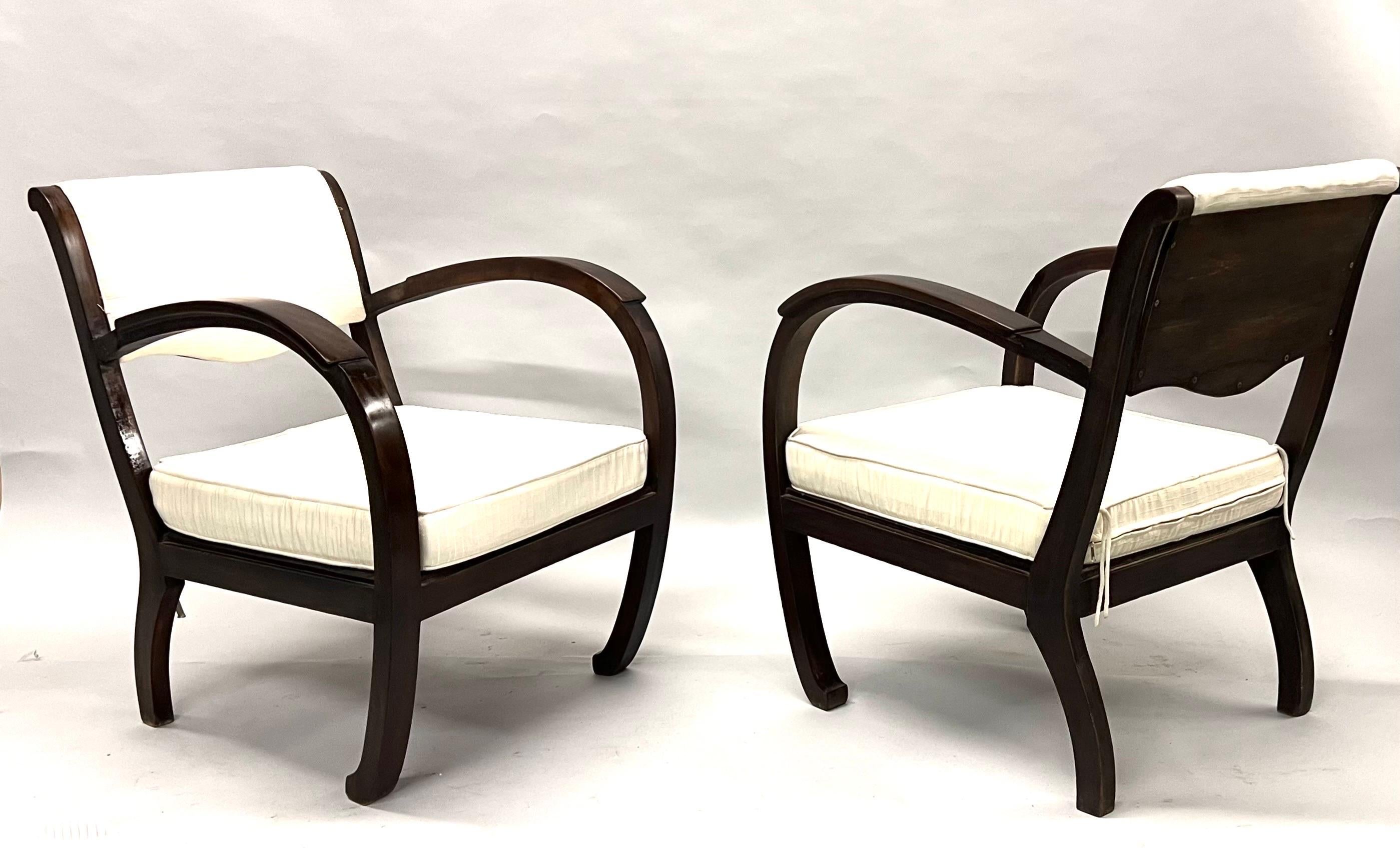 A Rare Pair of French Art Deco Hand Carved Teak armchairs / Lounge or Club Chairs circa 1920 - 1930. The chairs are hand made of pure, solid teak and possess a unique, iconic form. The arms are curved and sweeping and form a continuous arc with the
